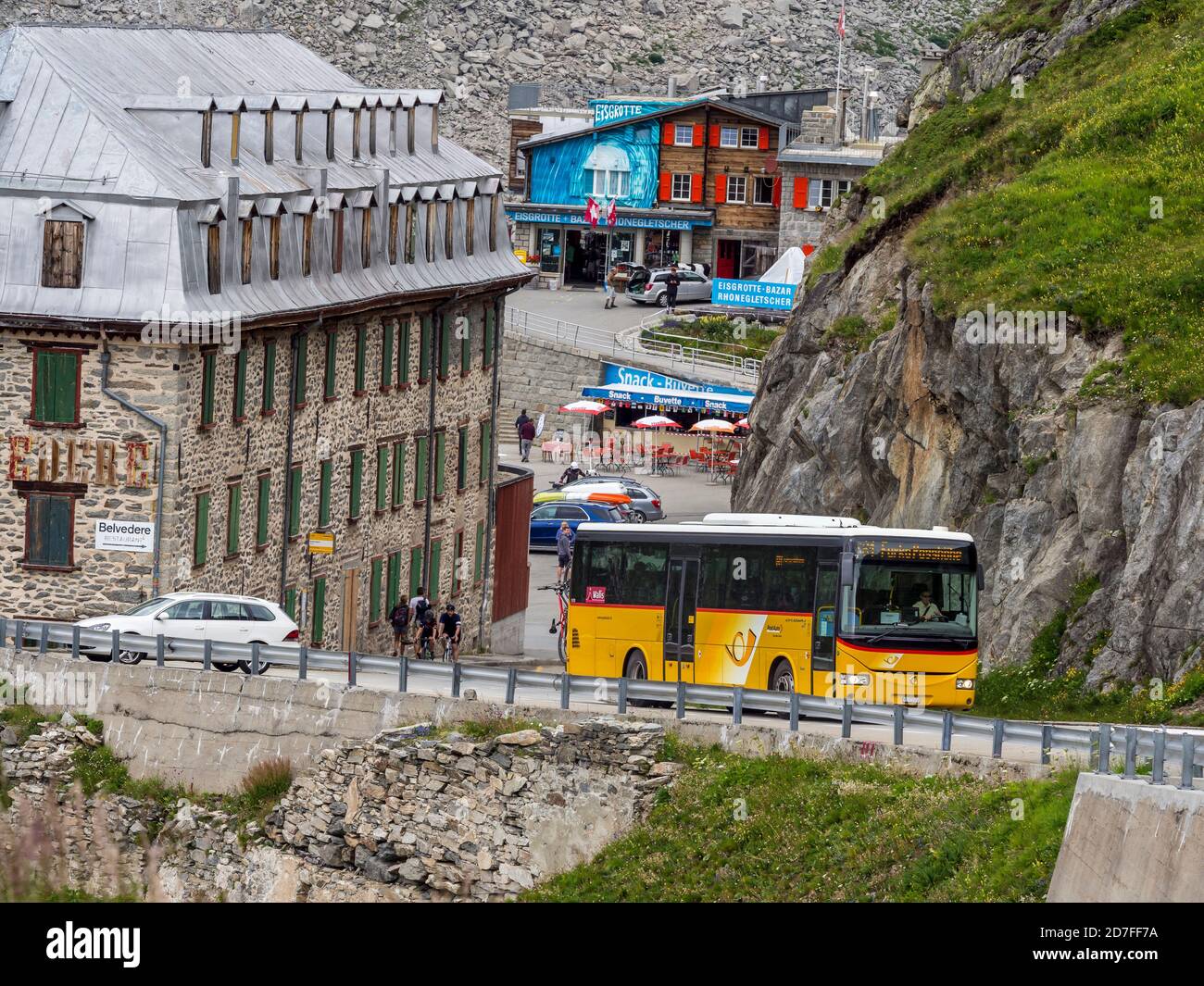 Autobus svizzero giallo sulla strada presso l'hotel Belvedere chiuso, Passo Furka, Svizzera. Foto Stock