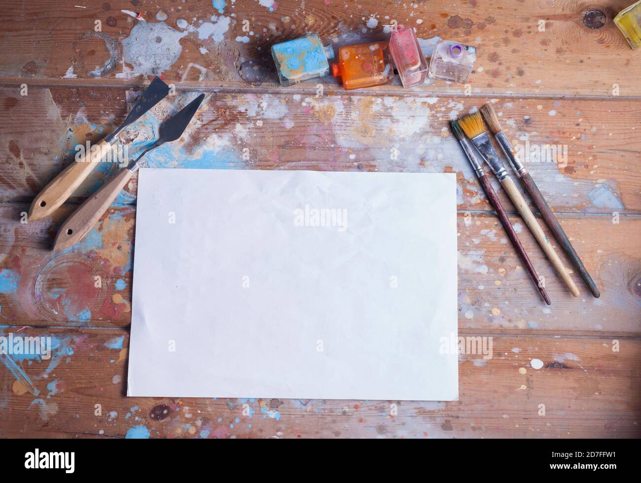 Artisti scrivania e materiali mockup.vari pennelli e pallete coltelli.l'immagine contiene un foglio bianco di carta ideale per un mockup creativo. Foto Stock