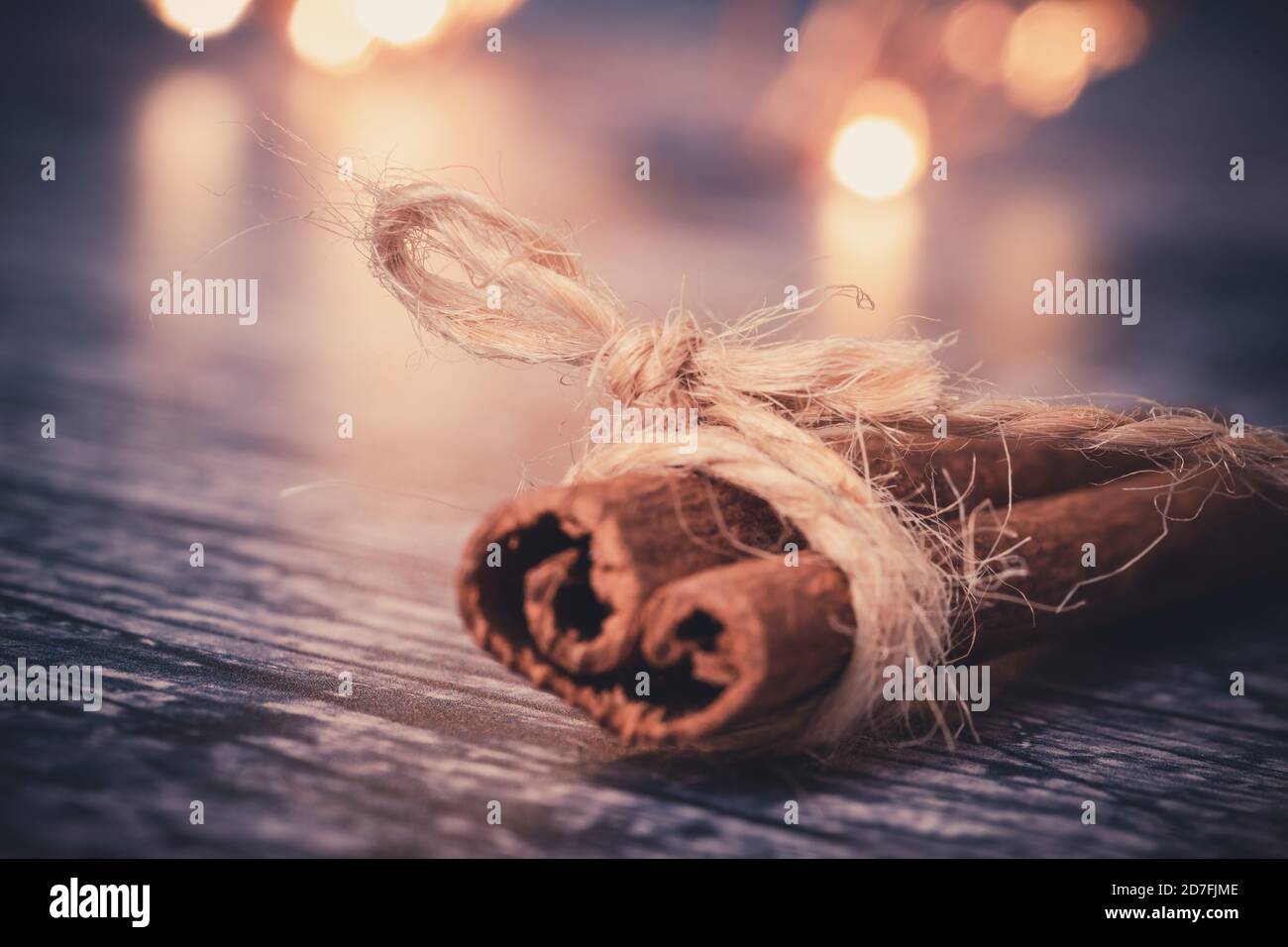 Primo piano di un bastone di cannella intorno al quale è avvolto un filo. Toni autunnali e luce bokeh sullo sfondo. Concetto di vacanze Foto Stock
