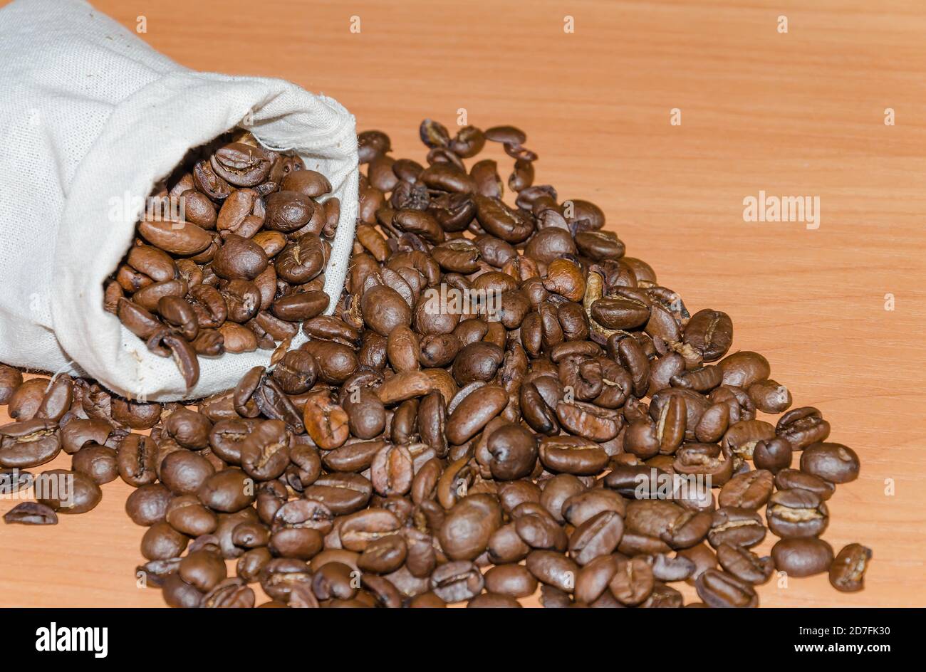 chicchi di caffè arrostiti, in un sacchetto su un tavolo di legno, primo piano Foto Stock