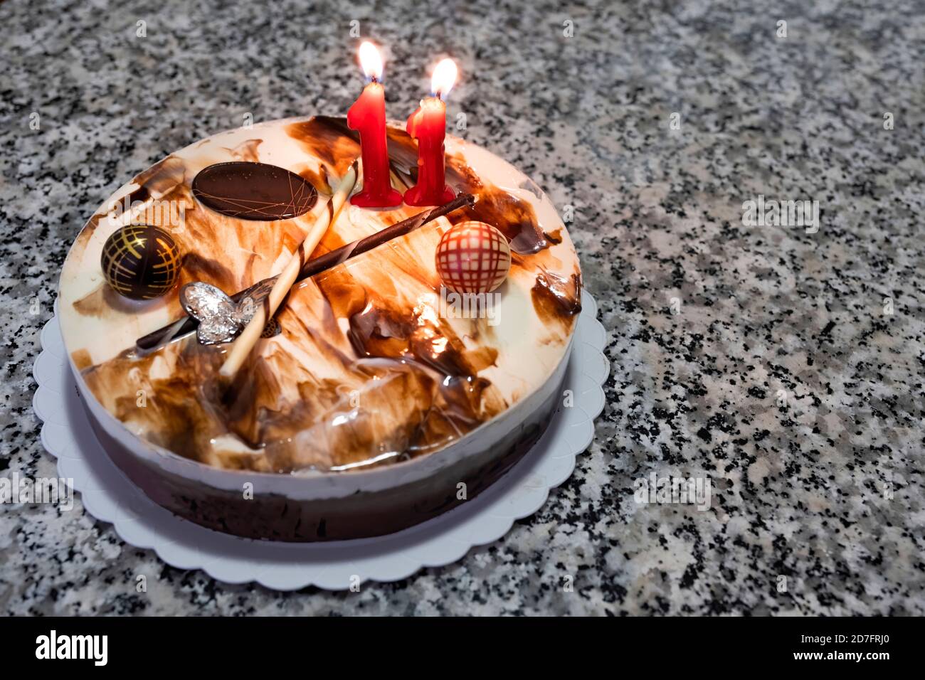 Tre torta al cioccolato con una candela di compleanno con il numero 11 e una barretta di cioccolato senza testo, torta di compleanno su un tavolo di marmo Foto Stock