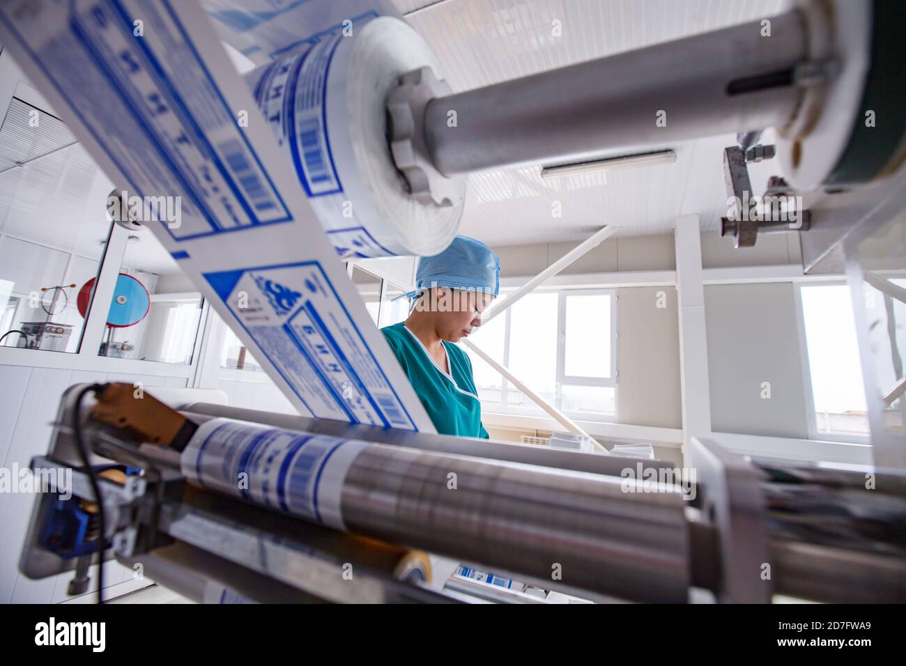 Taraz/Kazakhstan - Aprile 25 2012: Impianto medico Superfarm. Produzione di forniture mediche. Macchina impacchettatrice e operatore per rotoli di bendaggio. Foto Stock