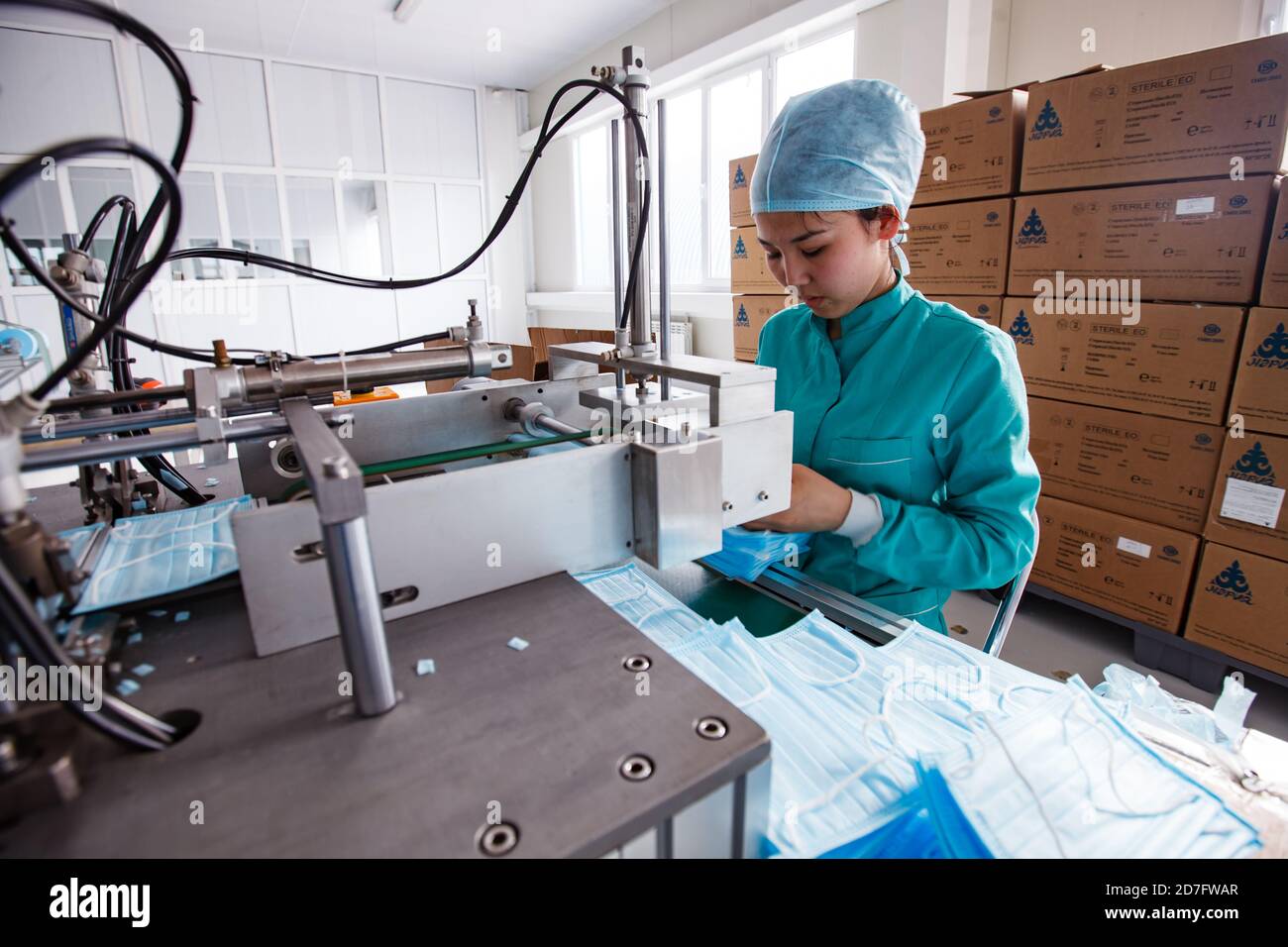 Taraz/Kazakhstan - Aprile 25 2012: Impianto medico Superfarm. Produzione di forniture mediche. Linea di produzione di maschere facciali e giovane operatore asiatico. Foto Stock