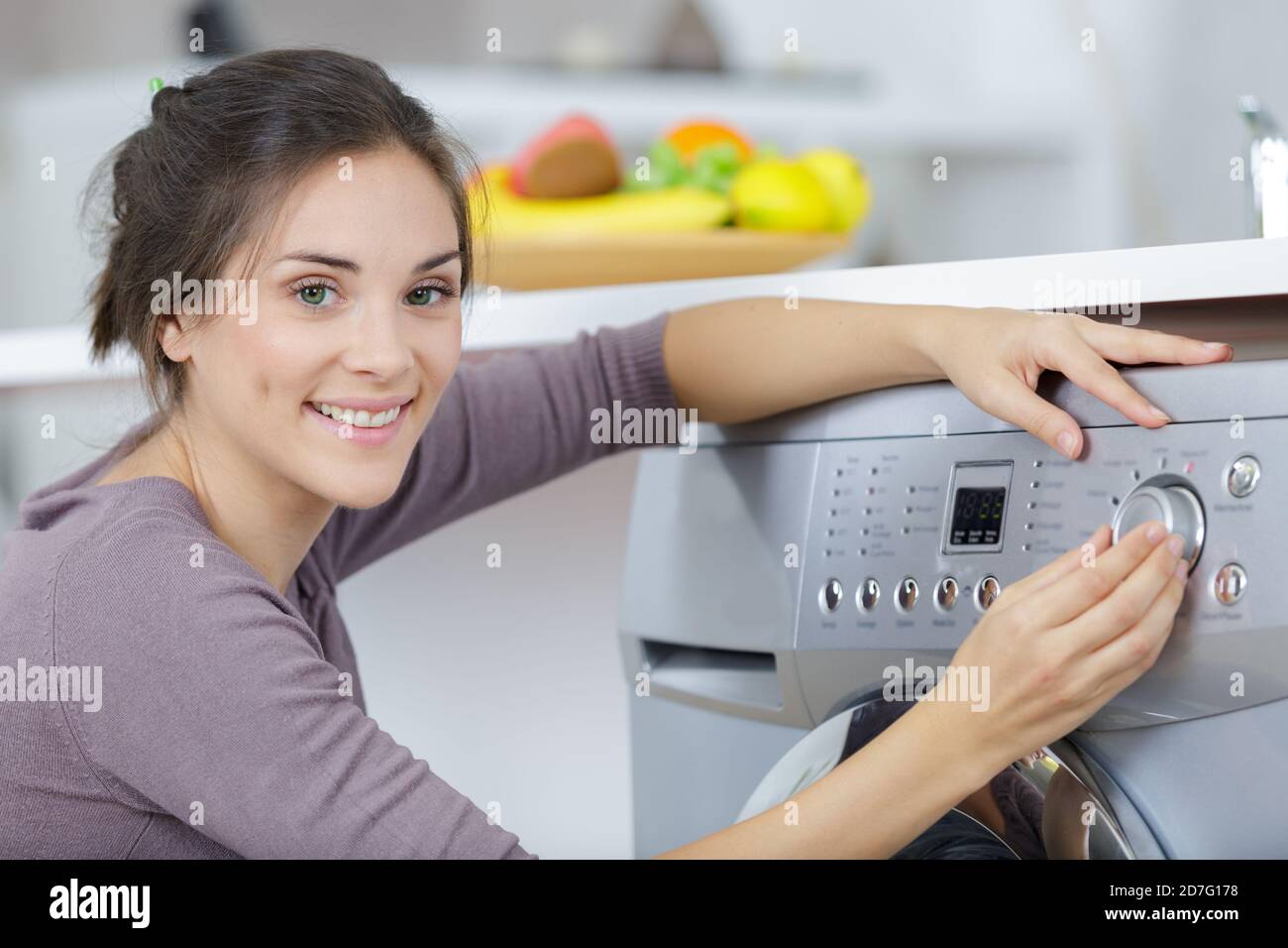 ritratto di donna che sceglie il programma sulla lavatrice Foto Stock