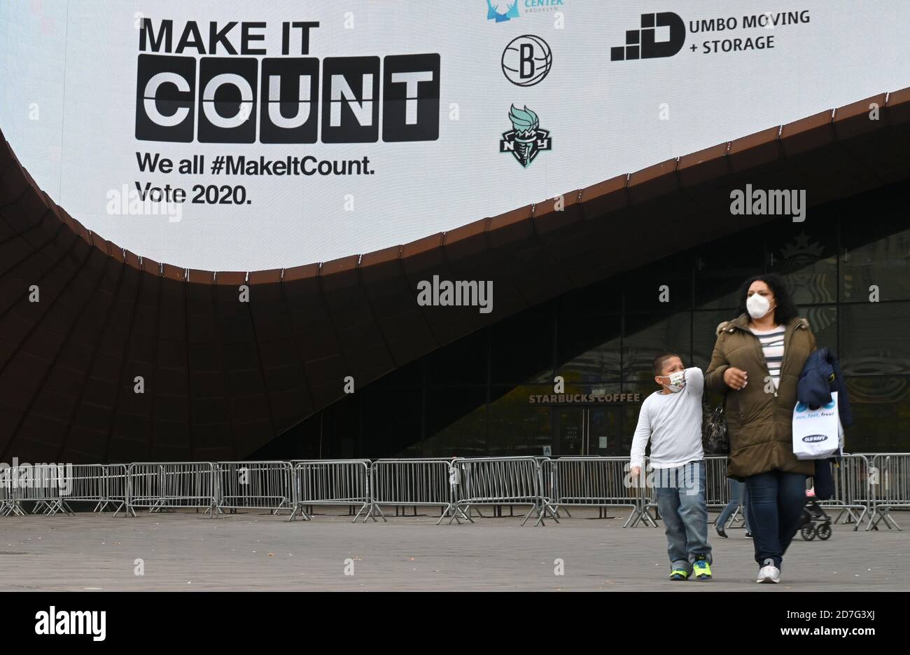 New York City, Stati Uniti. 22 ottobre 2020. Una donna e un bambino camminano sotto un segno che incoraggia la gente a votare nelle prossime elezioni presidenziali degli Stati Uniti, fissate sul bordo esterno del Barclays Center, nel quartiere Brooklyn di New York City, NY, 22 ottobre 2020. Il Consiglio delle elezioni costituirà i primi centri di voto a partire da sabato 24 ottobre in luoghi sportivi come il Barclays a Brooklyn e il Madison Square Garden a Manhattan. (Anthony Behar/Sipa USA) Credit: Sipa USA/Alamy Live News Foto Stock