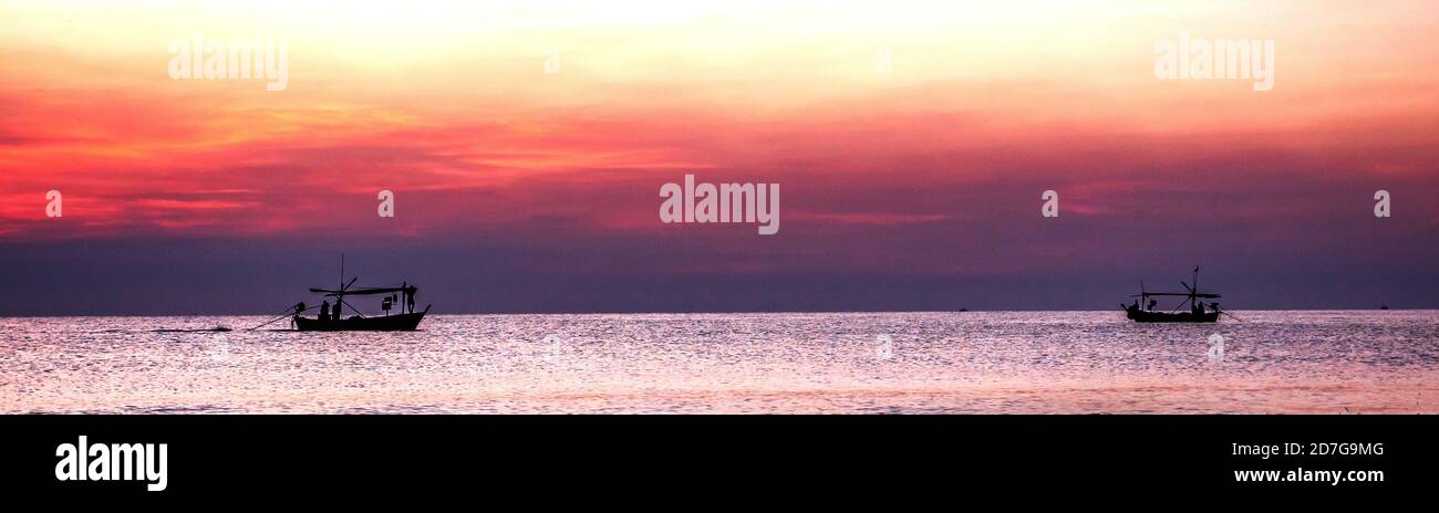 Silhouette di barca da pesca in mare al tramonto Foto Stock