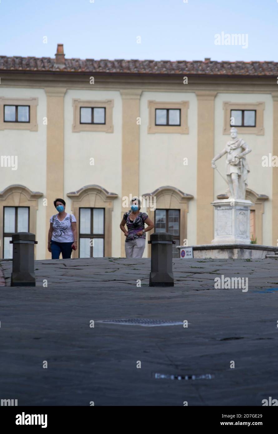 Due turisti che indossano maschere passeggiano attraverso la città di Arezzo Foto Stock