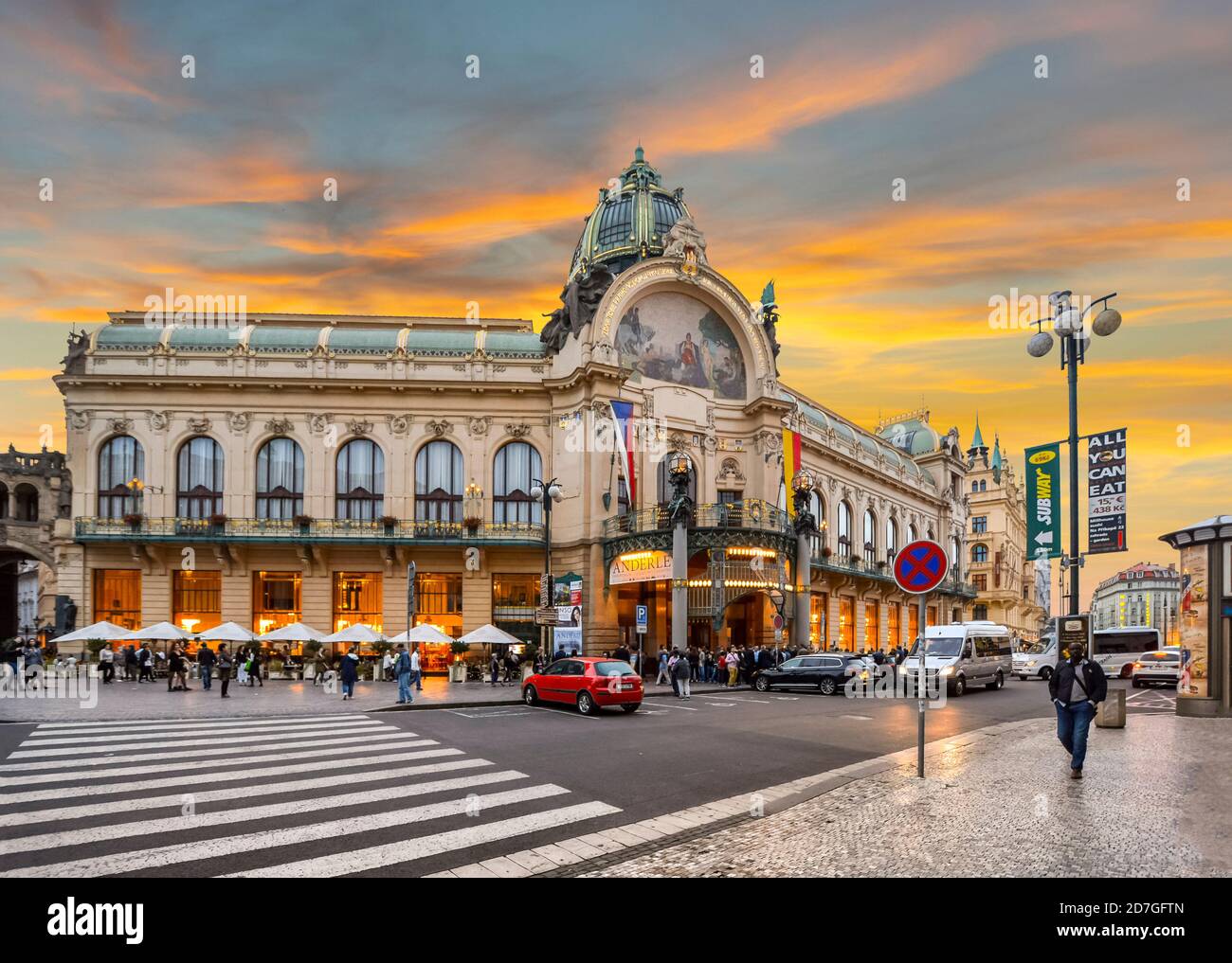 Il sole si stabilisce a New Town Prague, Repubblica Ceca, mentre la gente del posto attraversa la strada principale di fronte al Municipio di Praga. Foto Stock