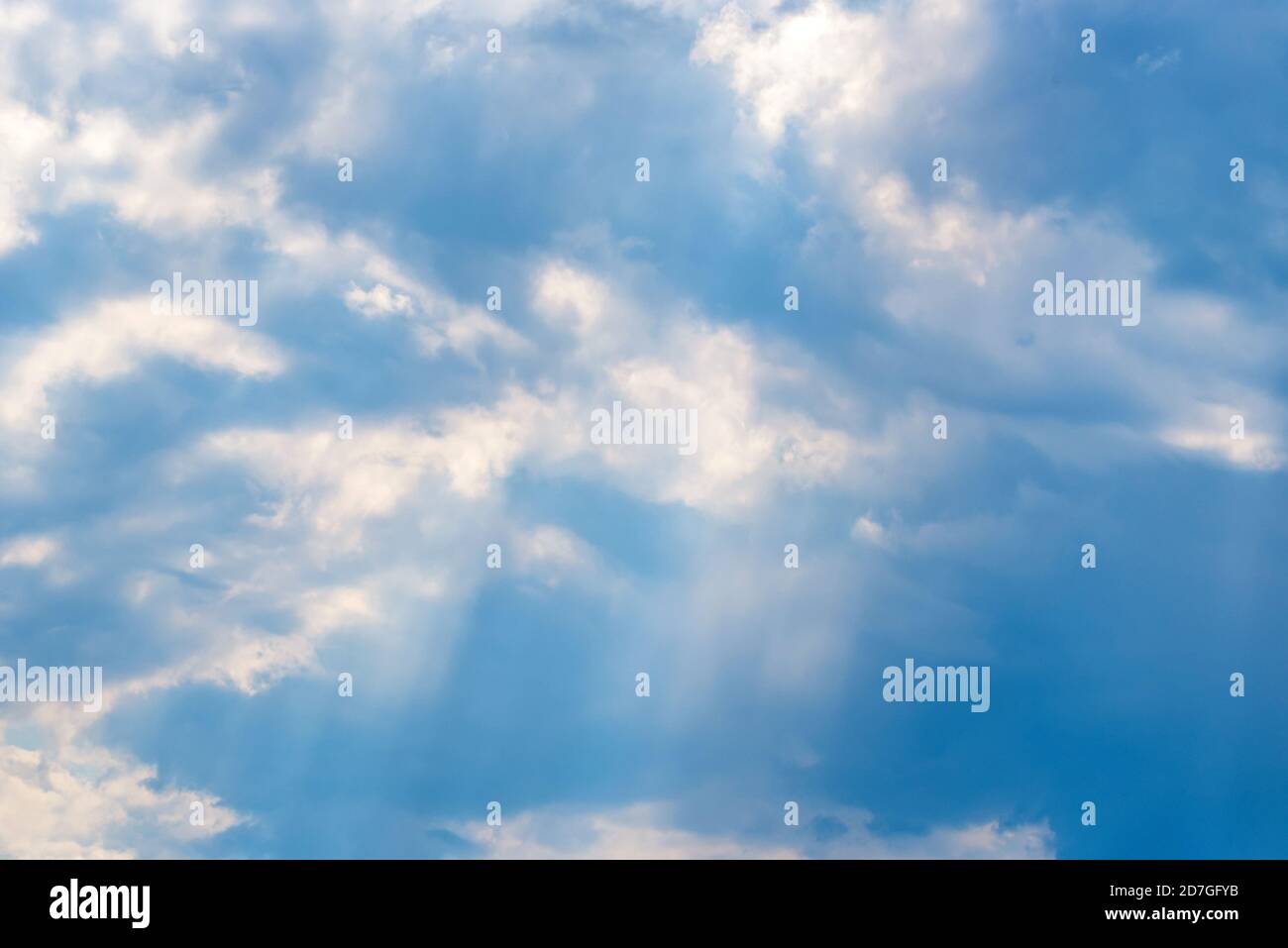 Raggi solari che cadono dalle nuvole sul cielo blu Foto Stock