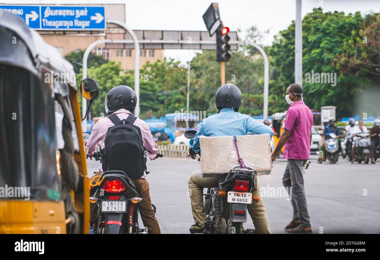 I motociclisti aspettano all'incrocio di Valluvar Kottam. Un uomo che indossa una maschera facciale e traffico sfocato sullo sfondo. Foto Stock