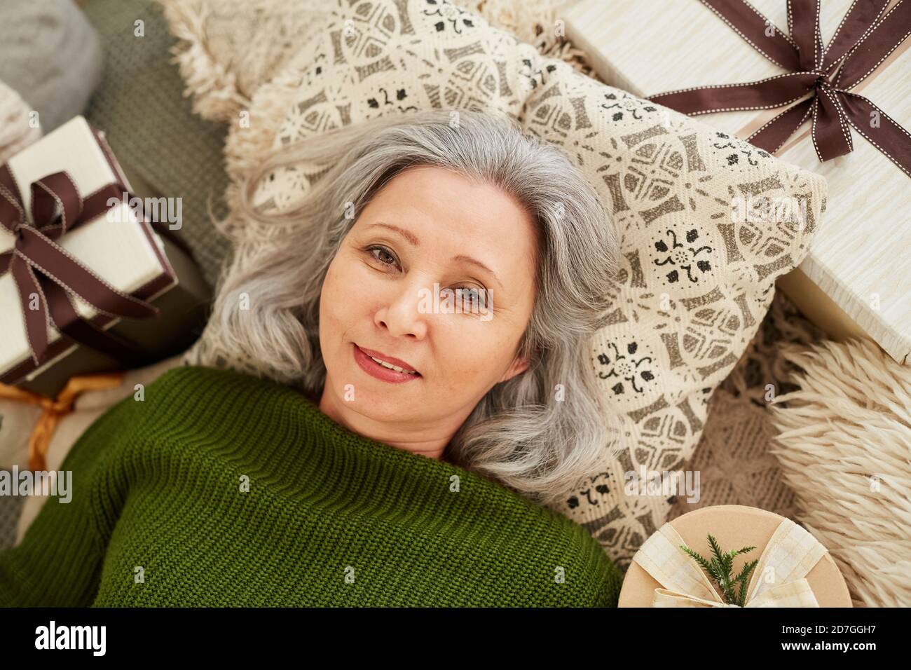 Vista ad alto angolo di una donna matura che giace sul cuscino presenta il riposo e la vista della fotocamera Foto Stock