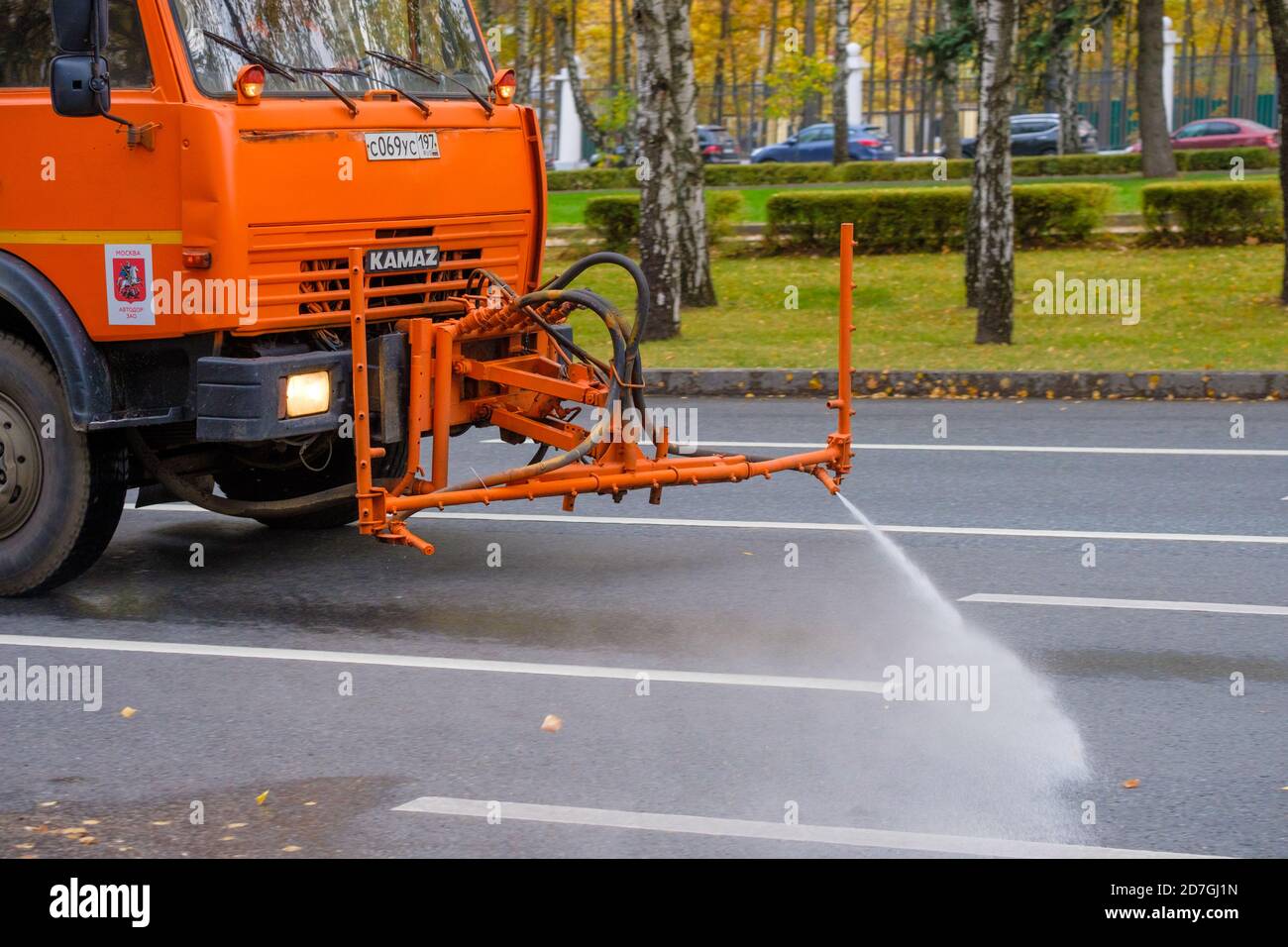 Mosca. Russia. 11 ottobre 2020. Un camion pesante arancione lava le foglie autunnali fuori dalla strada asfaltata. Il lavoro dei servizi pubblici in città. Autunno Foto Stock