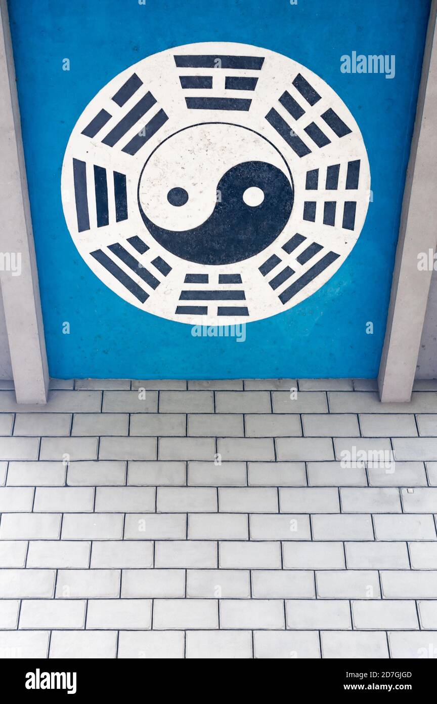 Simbolo Yin e Yang su sfondo blu sopra a. Muro di mattoni in Cina Foto Stock