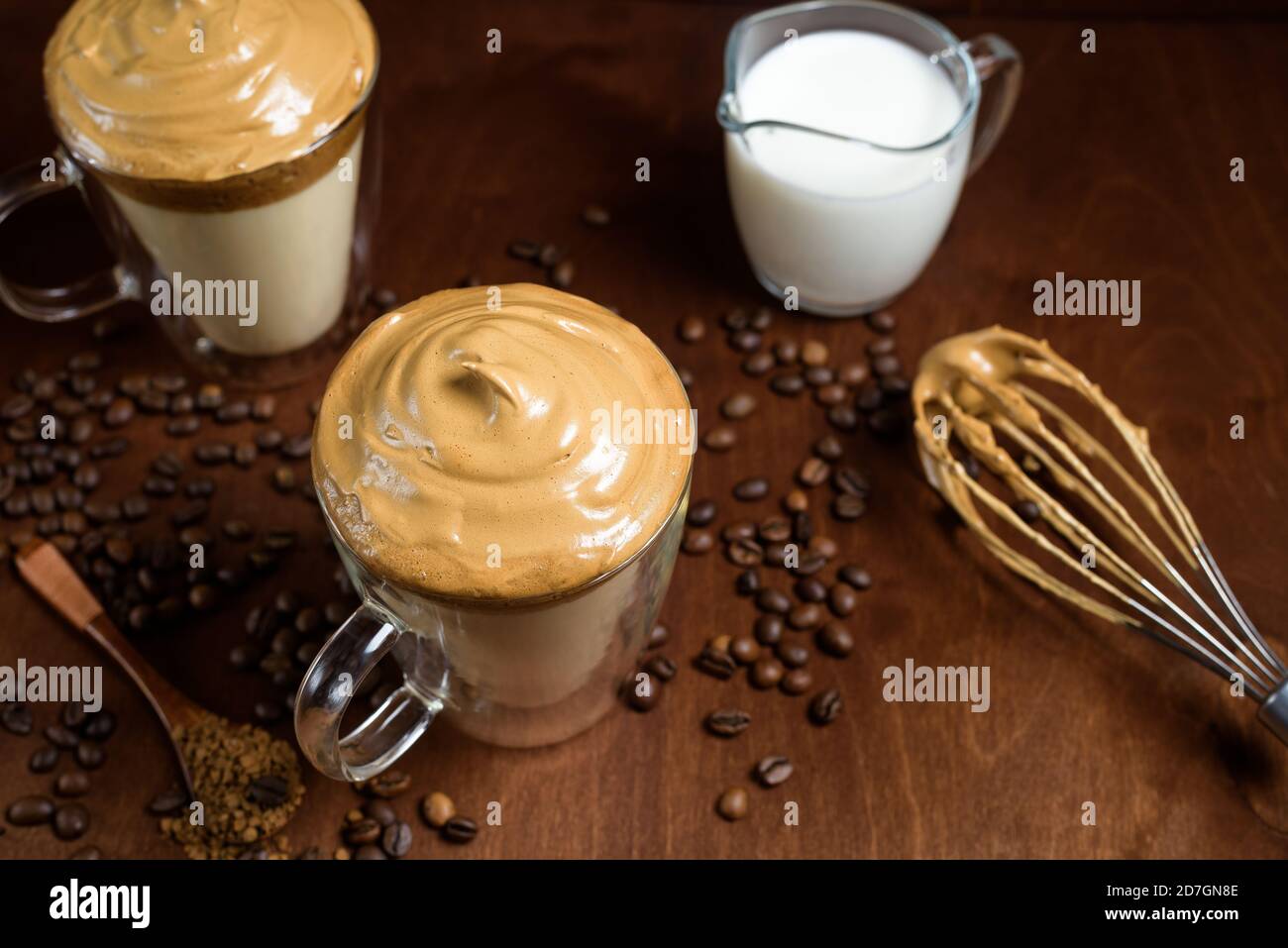 caffè di algone freddo in bicchieri trasparenti su fondo di legno scuro. schiuma di zucchero e caffè istantaneo viene montata con un miscelatore sul latte freddo. Coreano e. Foto Stock