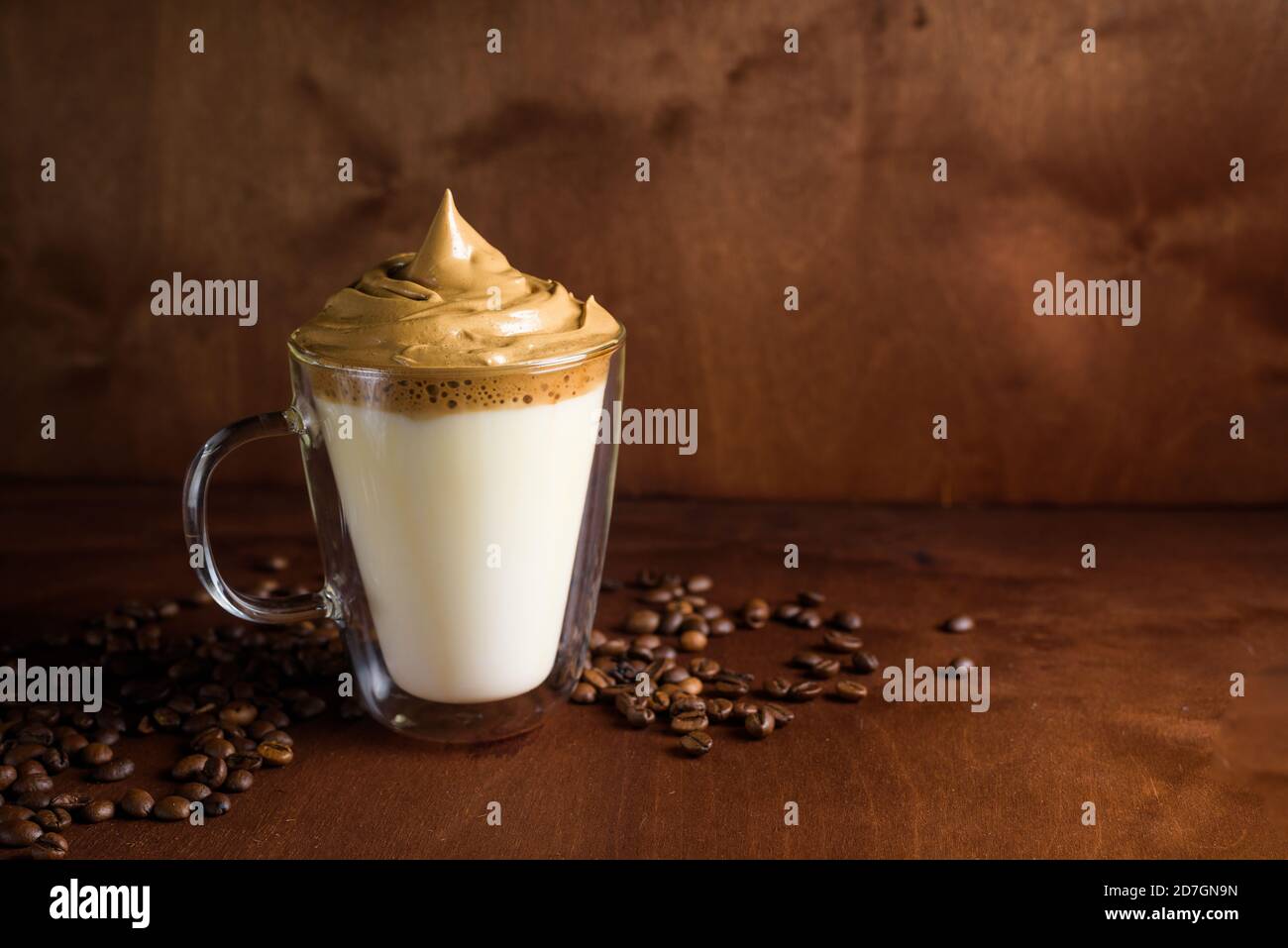 caffè dalgona freddo in bicchieri trasparenti su sfondo di legno scuro. schiuma di zucchero e caffè istantaneo montato con un mixer sopra latte freddo. primo piano Foto Stock