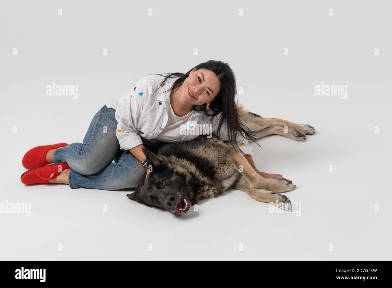 Sorridente donna asiatica che si trova in abbraccio con il cane pastore. Isolato su sfondo bianco. Il concetto preferito degli animali domestici Foto Stock