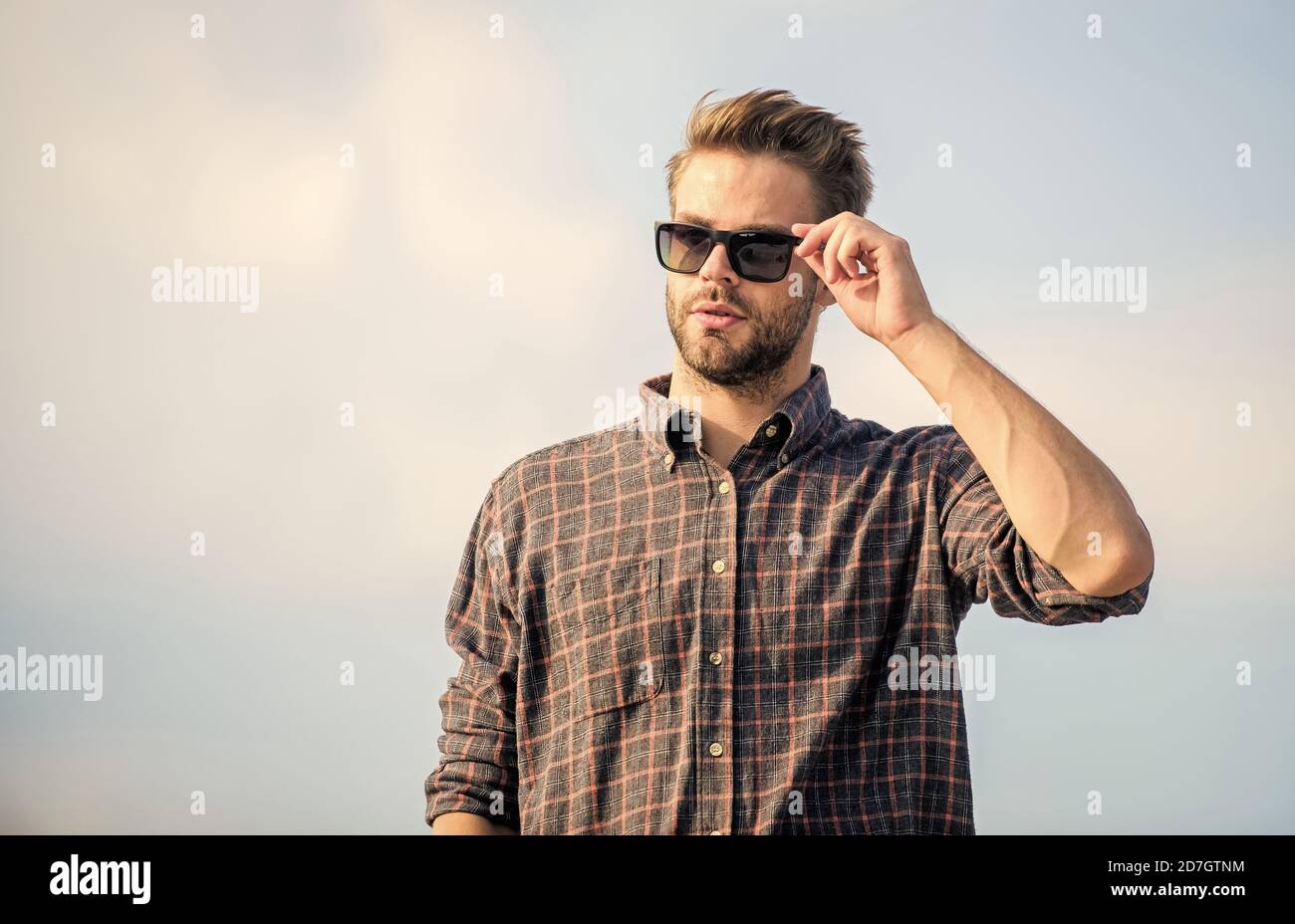 Vedere chiaro. Bel ragazzo indossare occhiali da sole. Hipster uomo in occhiali da sole alla moda. Occhiali da sole alla moda. Concetto di protezione ultravioletta. Modello uomo occhiali esterni blu cielo sfondo. Visione perfetta. Foto Stock