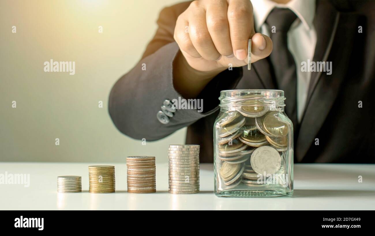 Gli uomini d'affari stanno tenendo i soldi in una bottiglia dei soldi per risparmiare i soldi per le idee di investimento, il risparmio dei soldi e gli investimenti sostenibili. Foto Stock