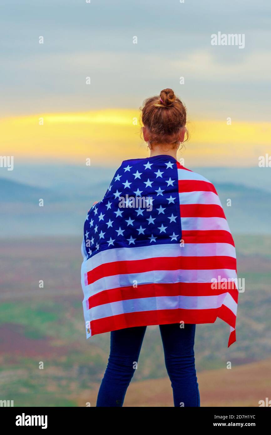 Giovane bambina che tiene bandiera degli Stati Uniti d'America al tramonto all'aperto. Foto Stock