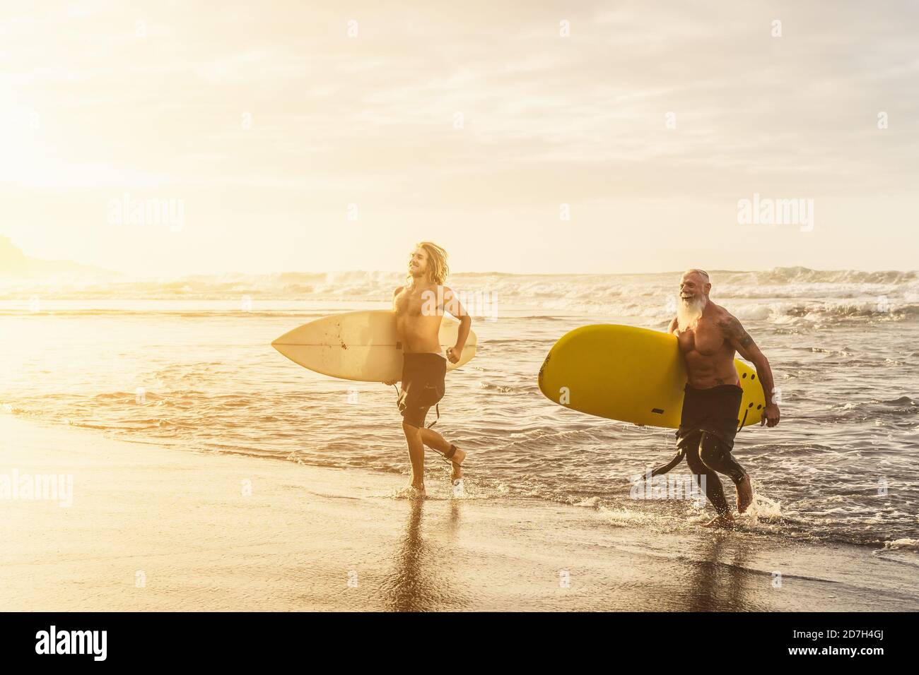 Amici felici con diverse età surf insieme sull'oceano tropicale - persone sportive che si divertono durante la giornata di surf vacanze Foto Stock