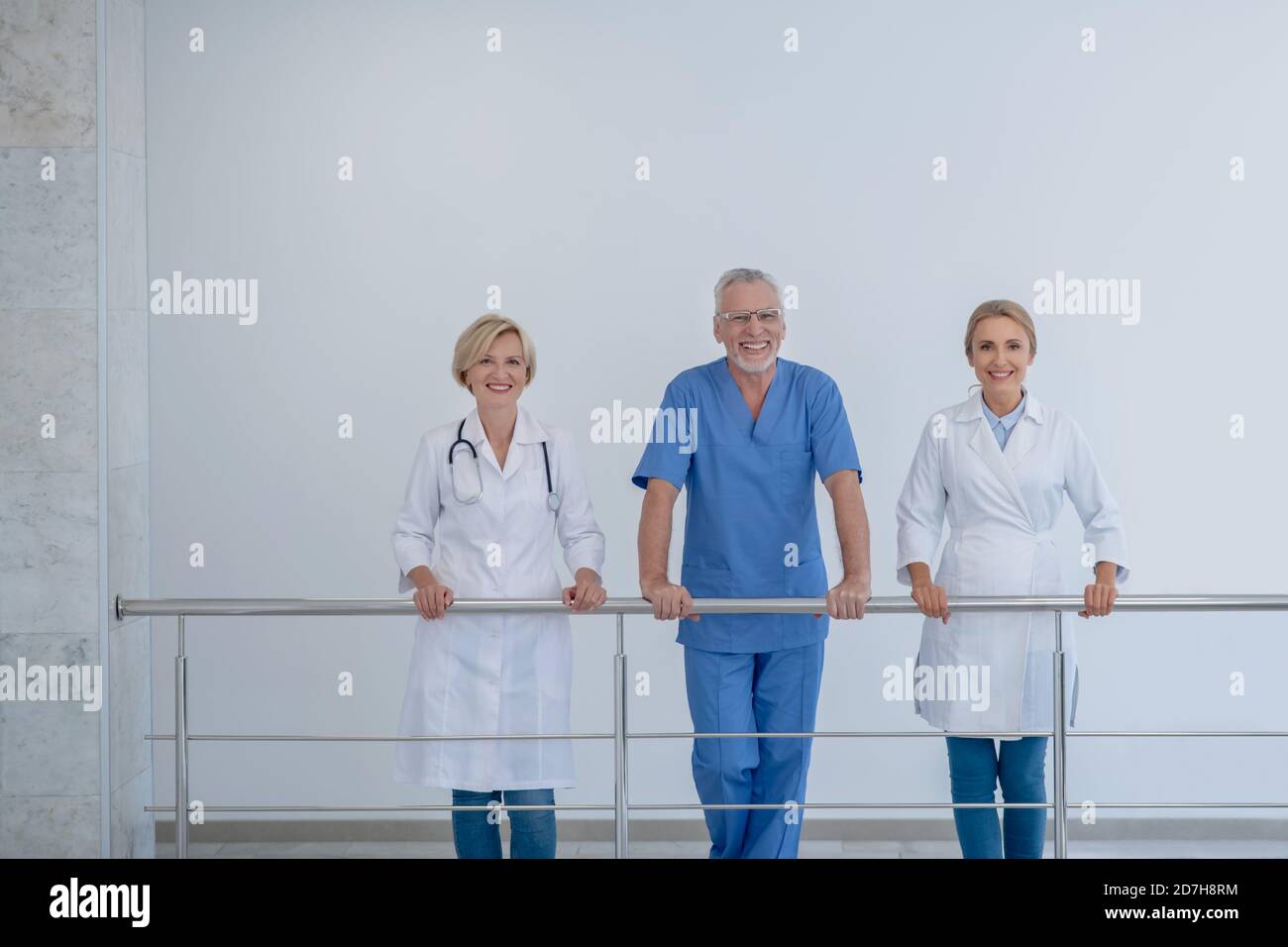 Sorridente team ospedaliero appoggiato su ringhiera scala Foto Stock
