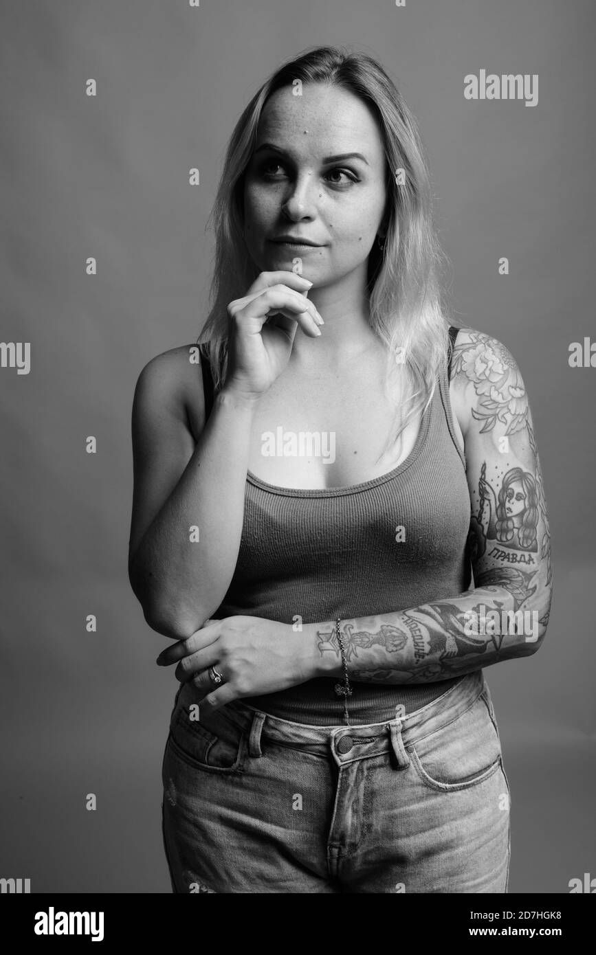 Giovane bella donna con capelli biondi contro uno sfondo grigio Foto Stock
