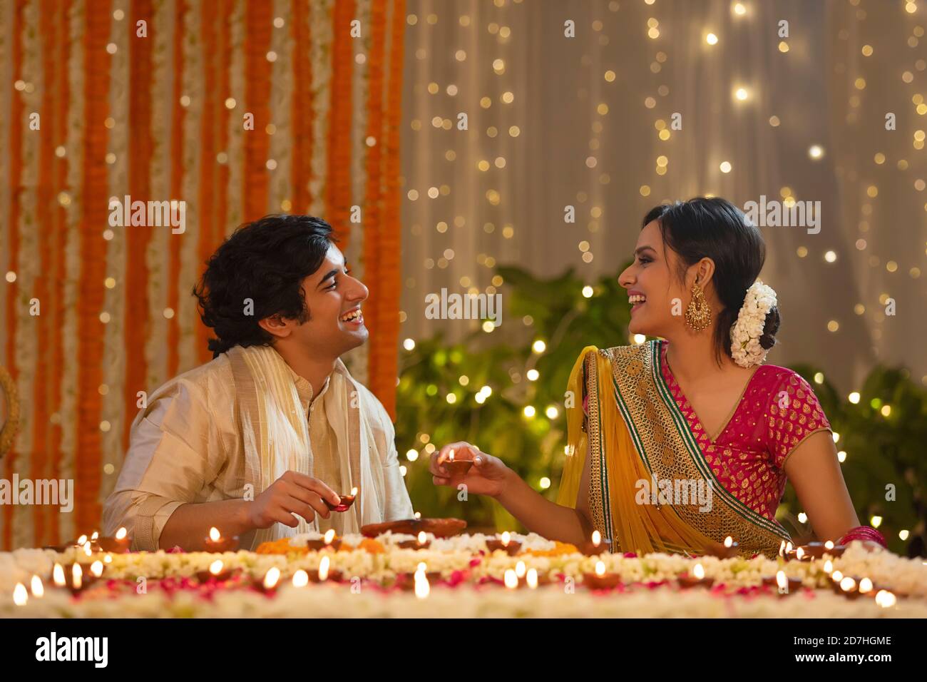 Giovane coppia ridendo insieme mentre illumina diya per diwali Foto Stock
