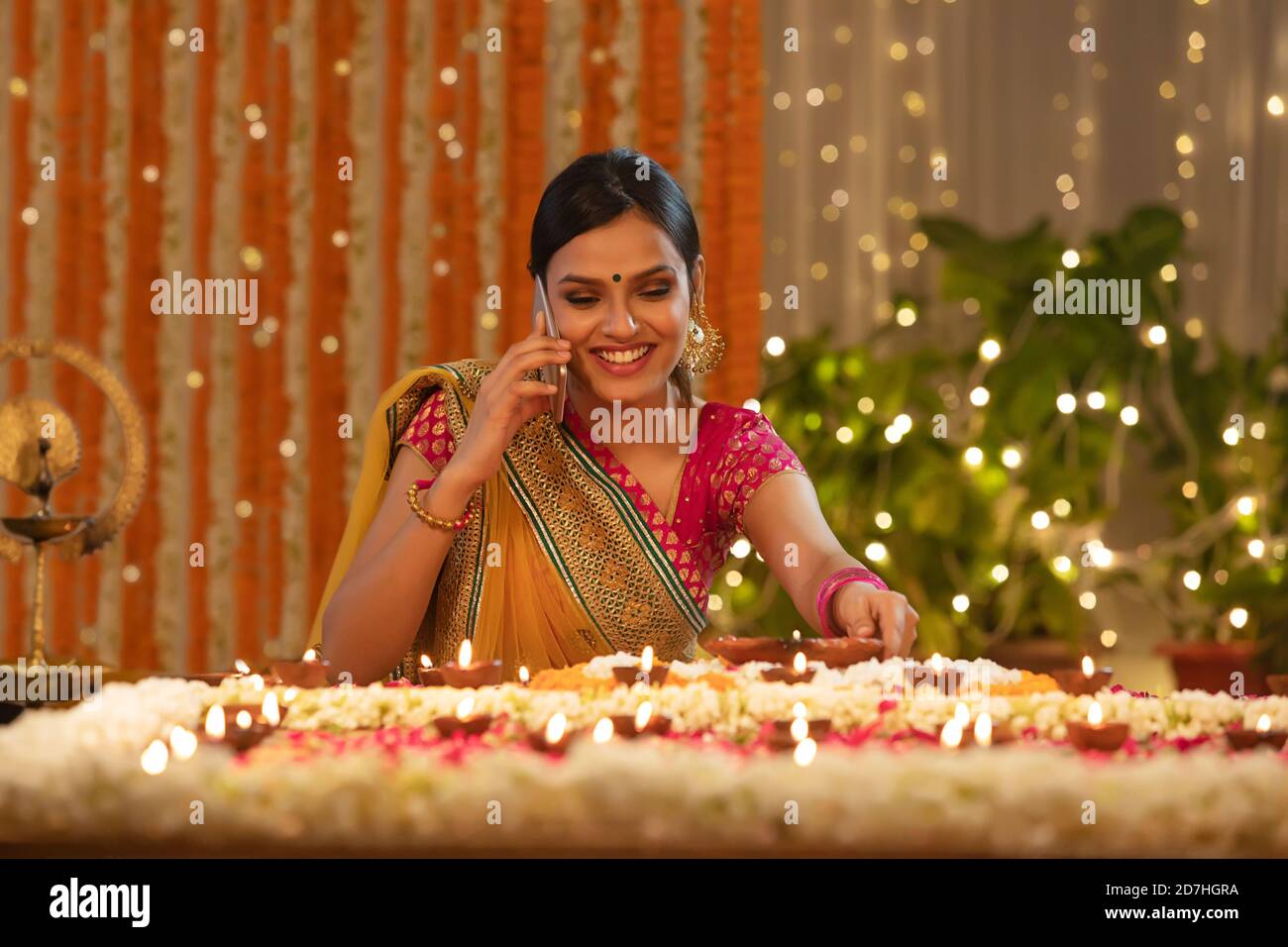 Giovane ragazza che mette diwali diya mentre è impegnato su un chiama Foto Stock