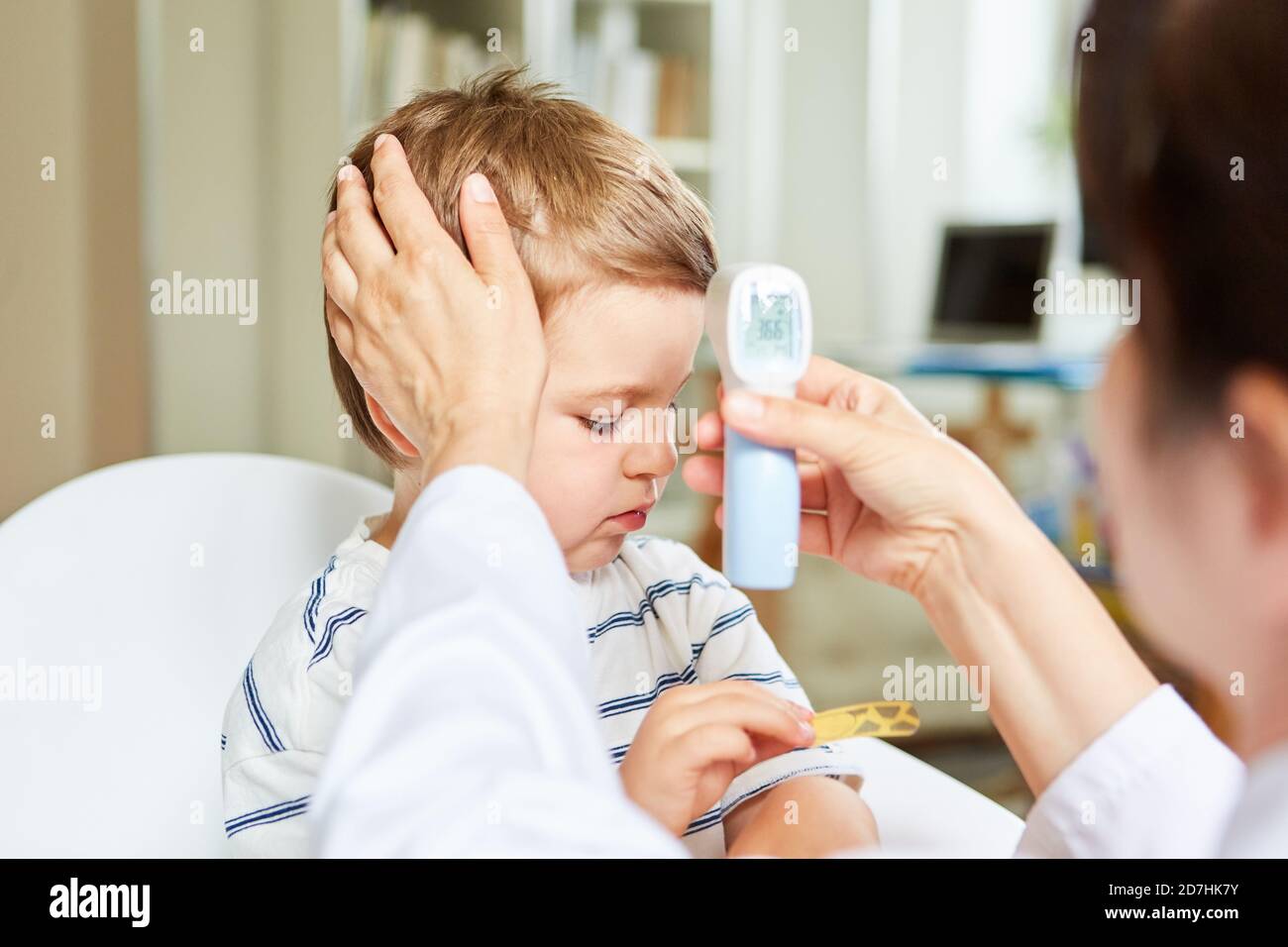 Pediatra e bambino malato che misura la febbre con l'infrarosso termometro per fronte Foto Stock