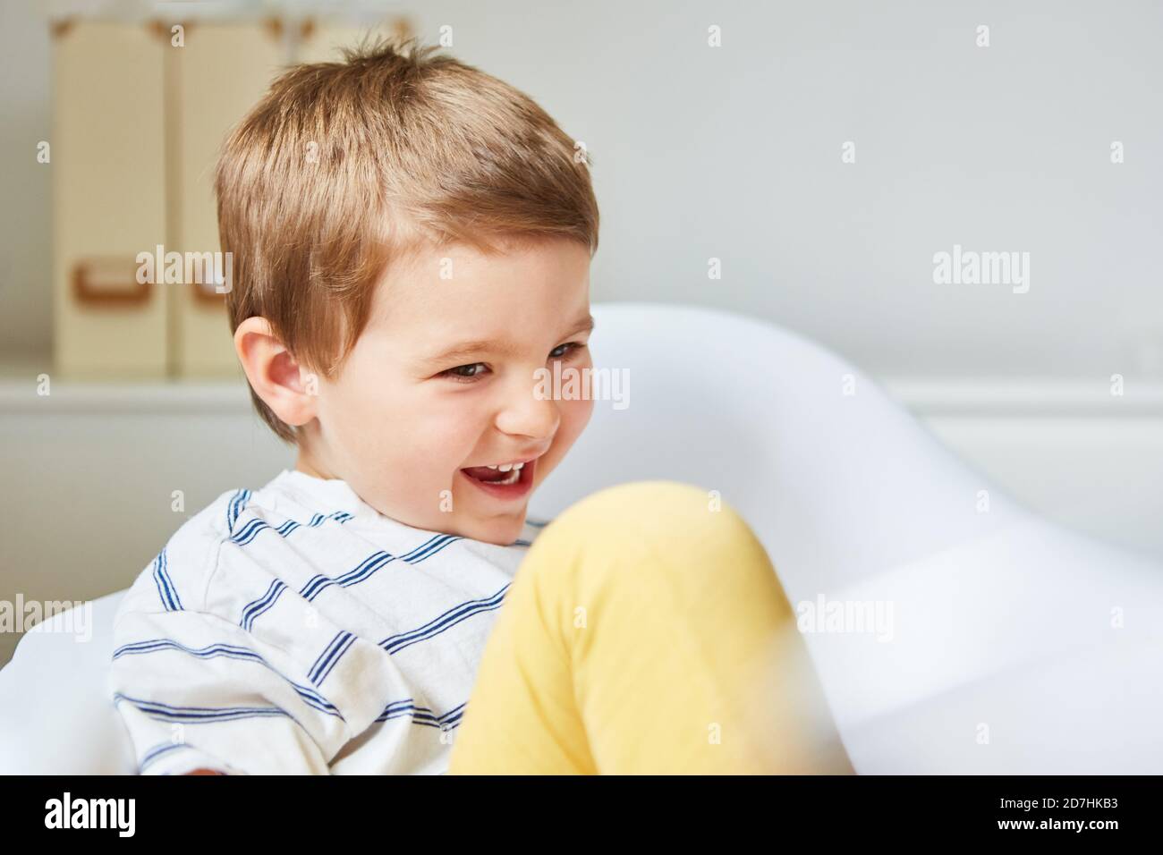 Ragazzo ridendo felice seduto su una sedia per la gioia di vita Foto Stock