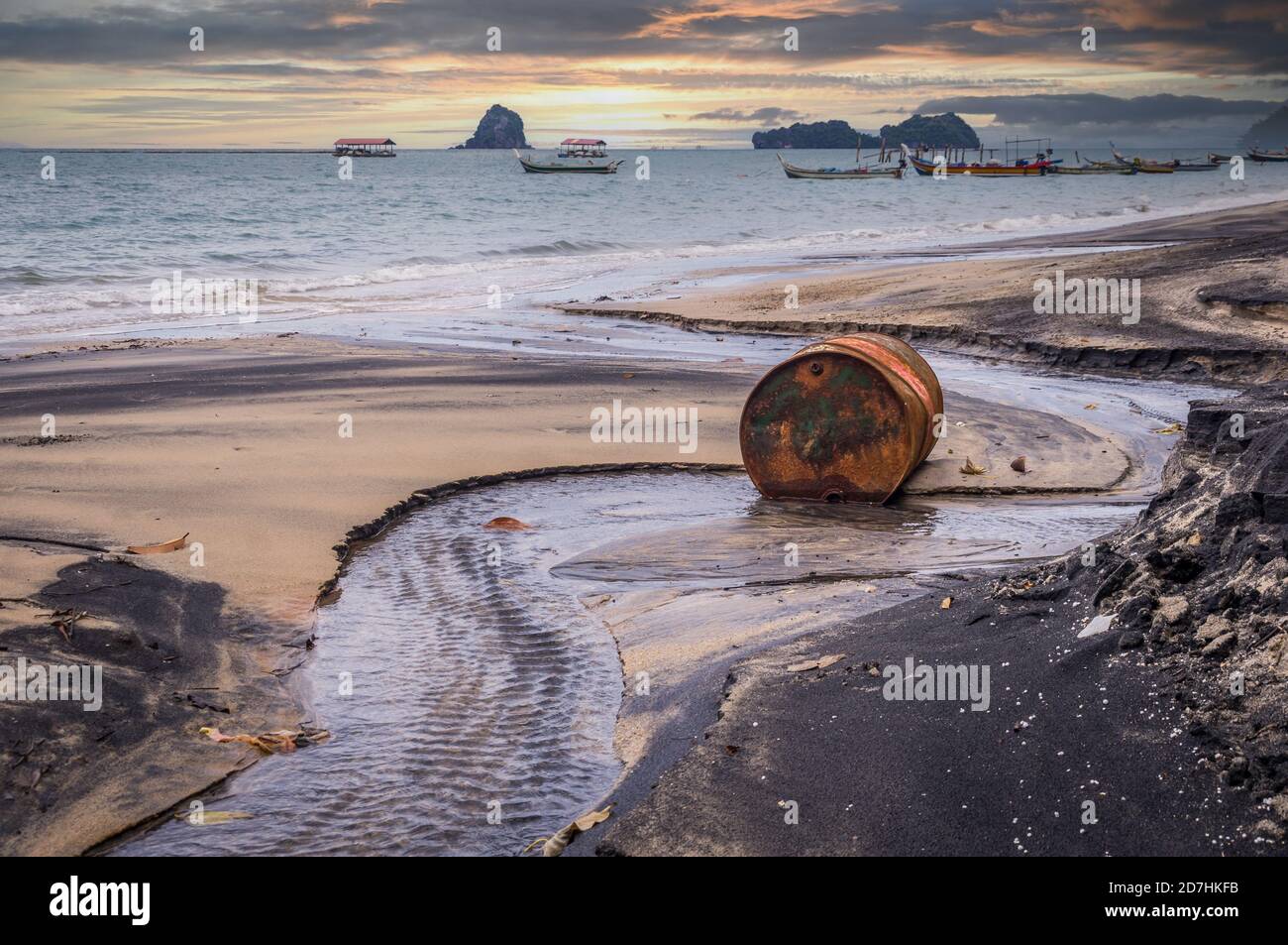 Vecchio olio di barile arrugginito sulla spiaggia in Asia al tramonto Foto Stock