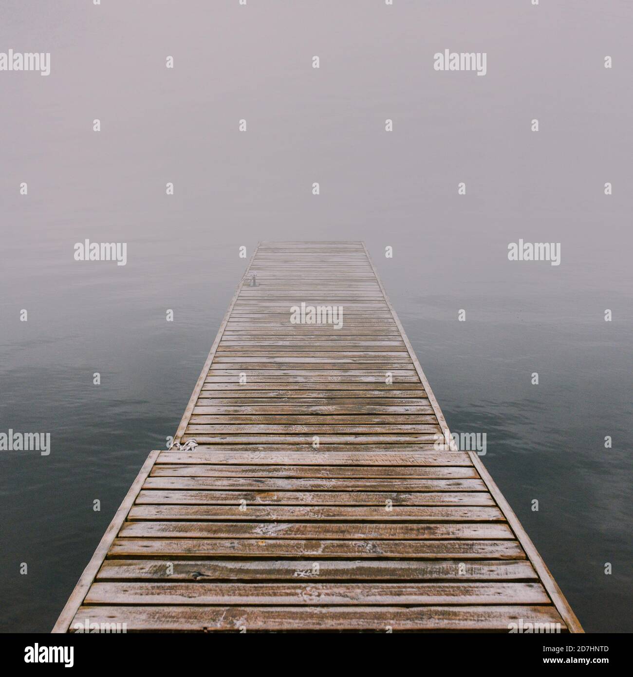 Molo di legno che va nella nebbia. Ponte misterioso vuoto sul fiume fatto di tavole. Tranquillo paesaggio nebbioso. Atmosfera suggestiva. Il concetto di Foto Stock