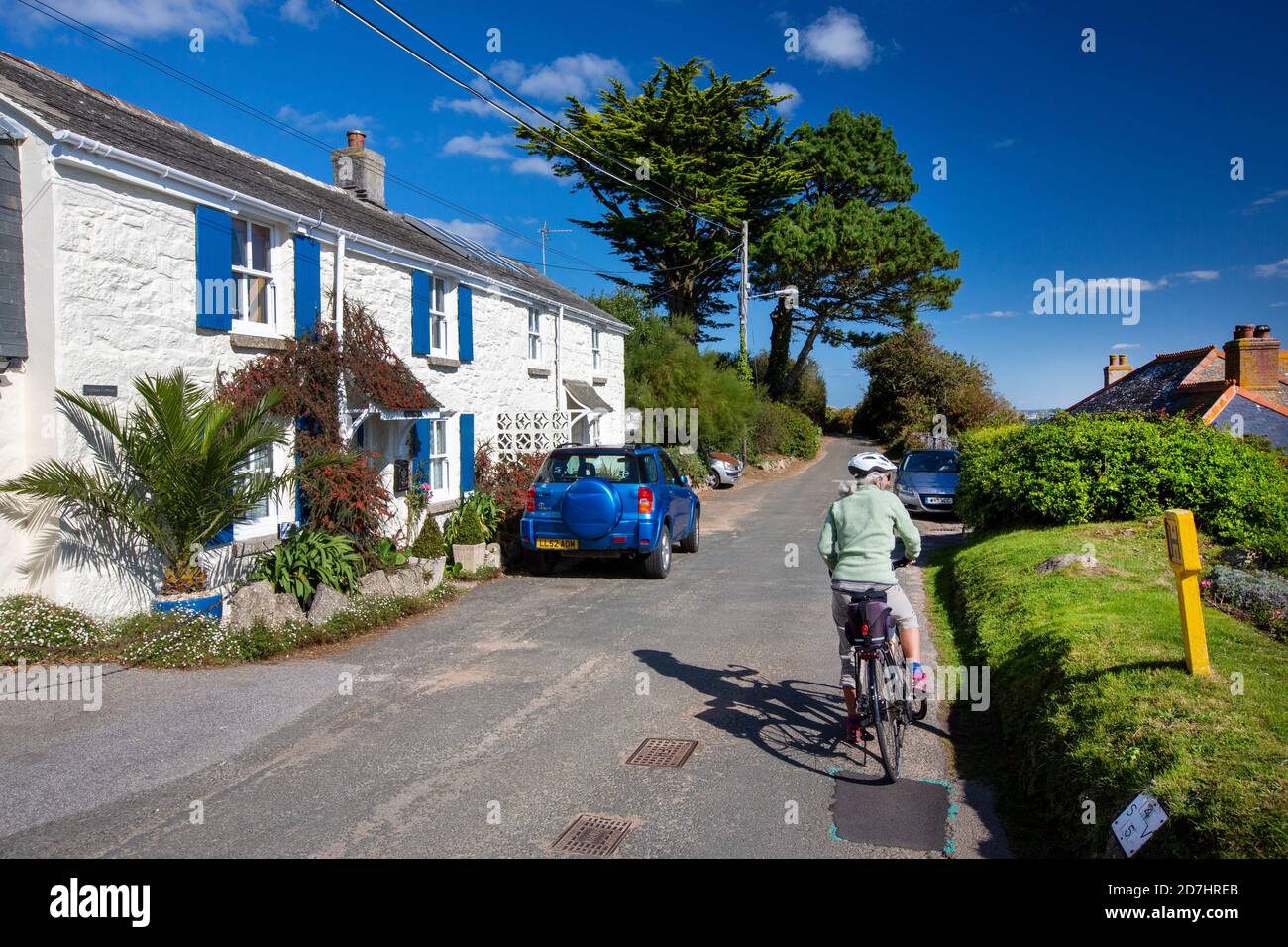 Una donna in bicicletta passato un vecchio cottage alla periferia di  Mousehole, Cornovaglia, Regno Unito Foto stock - Alamy