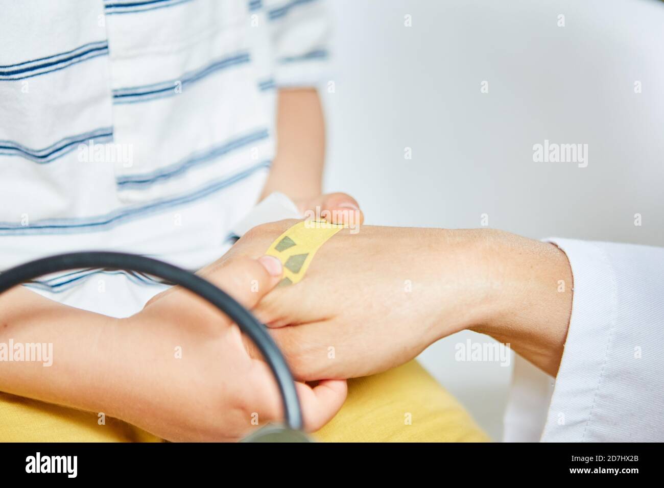 Il medico pratica il trattamento con un gesso sulla mano di il bambino come un esercizio contro la paura Foto Stock