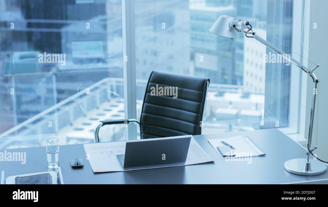 High Angle Shot di una scrivania di lavoro di una persona di successo in ufficio con vista città finestra. Foto Stock