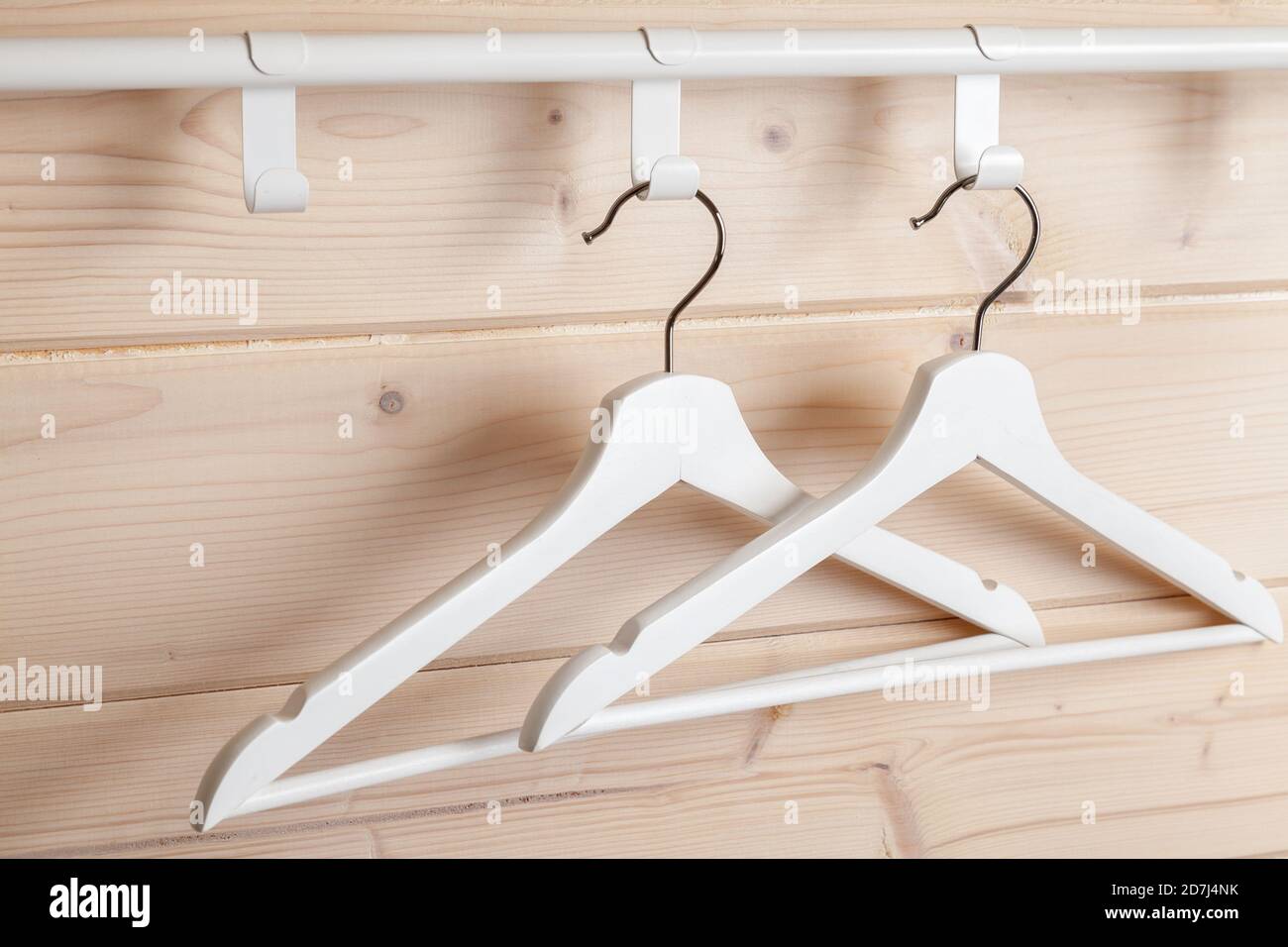 Due appendiabiti bianchi sono vicino a una parete di legno vuota, foto ravvicinata Foto Stock