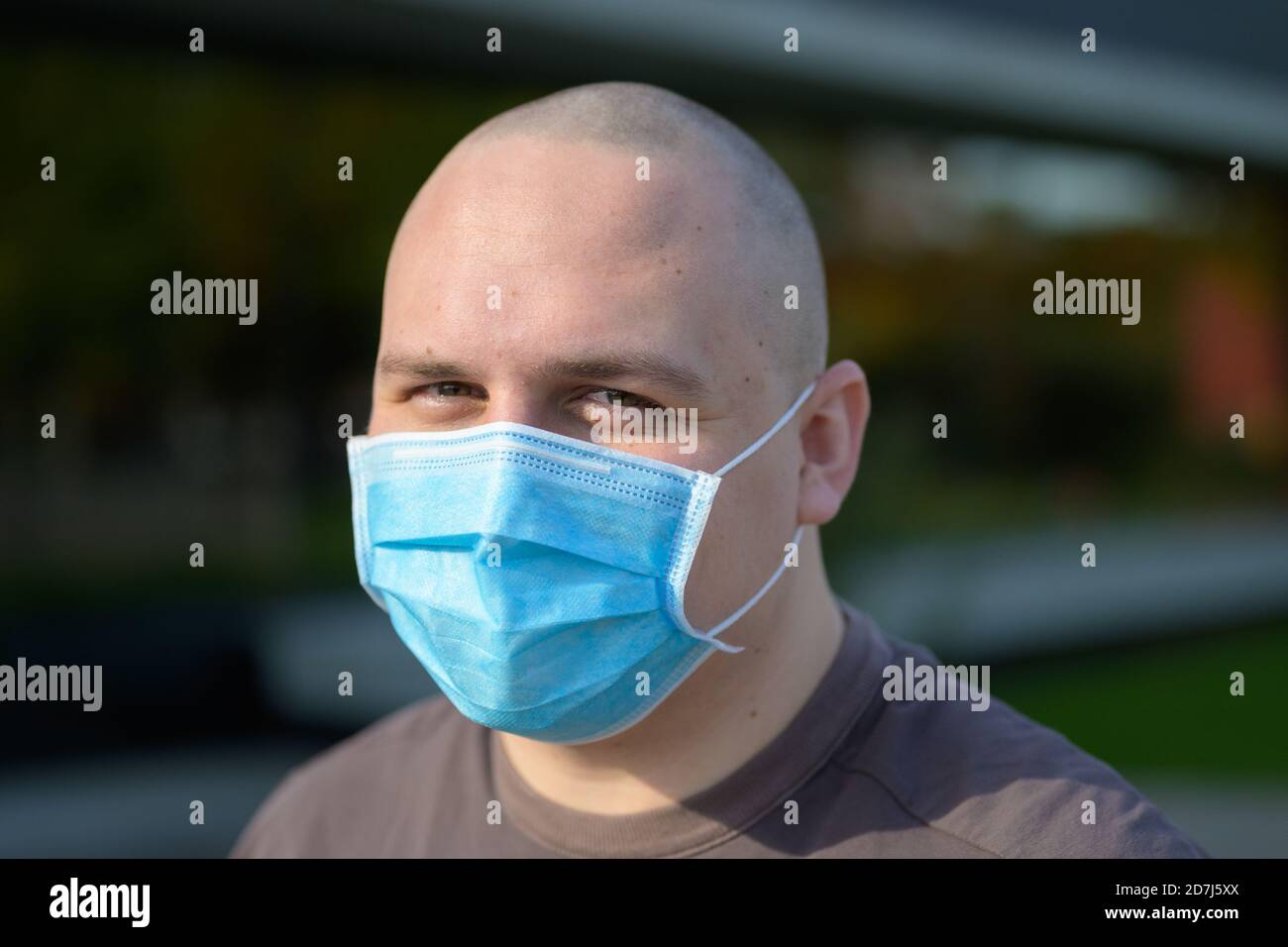 Giovane uomo con occhi sorridenti indossando una maschera durante Il Covid-19 o coronavirus pandemia come protezione contro le vie respiratorie virus in primo piano Foto Stock