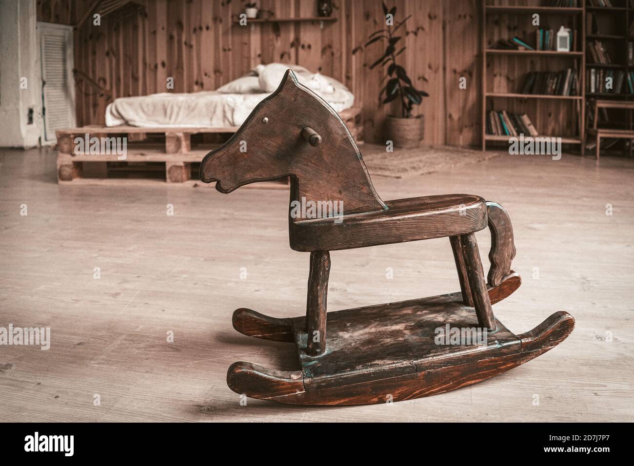 Antico cavallo giocattolo in legno sul pavimento di spaziosa camera da letto. Concetto di ricordi d'infanzia felici Foto Stock