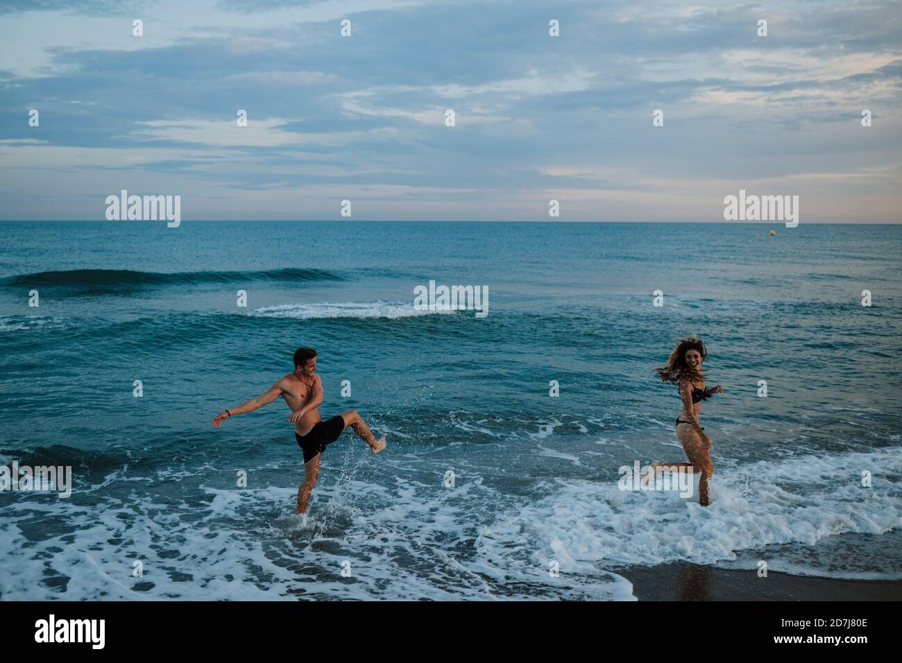 Giovane coppia che si diverse mentre si gioca in spiaggia Foto Stock