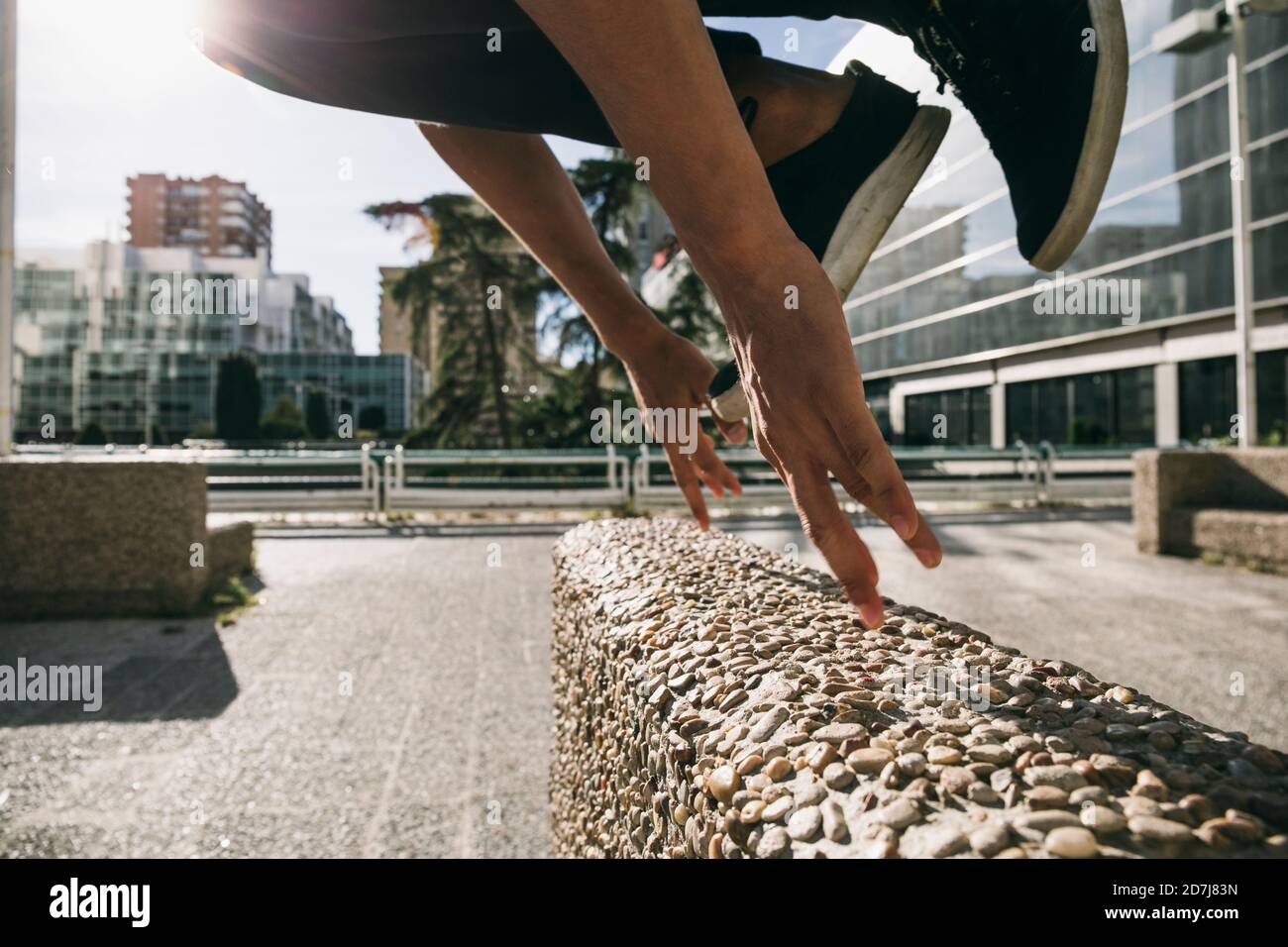 Gambe di un giovane uomo che salta sopra la parete eseguendo parkour in città Foto Stock