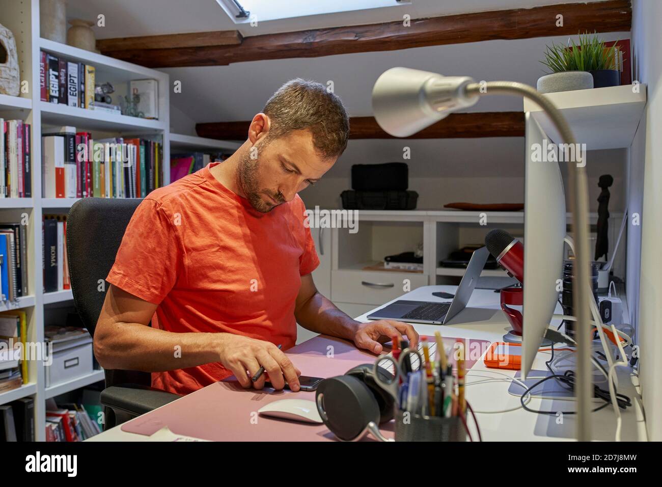 Messaggi di testo uomo sullo smartphone mentre si è seduti a casa Foto Stock