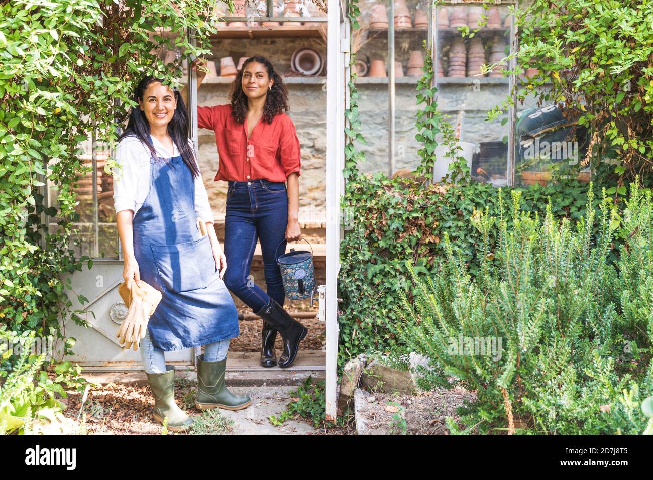 Amici in piedi nel cortile posteriore con attrezzatura da giardinaggio sul sole giorno Foto Stock