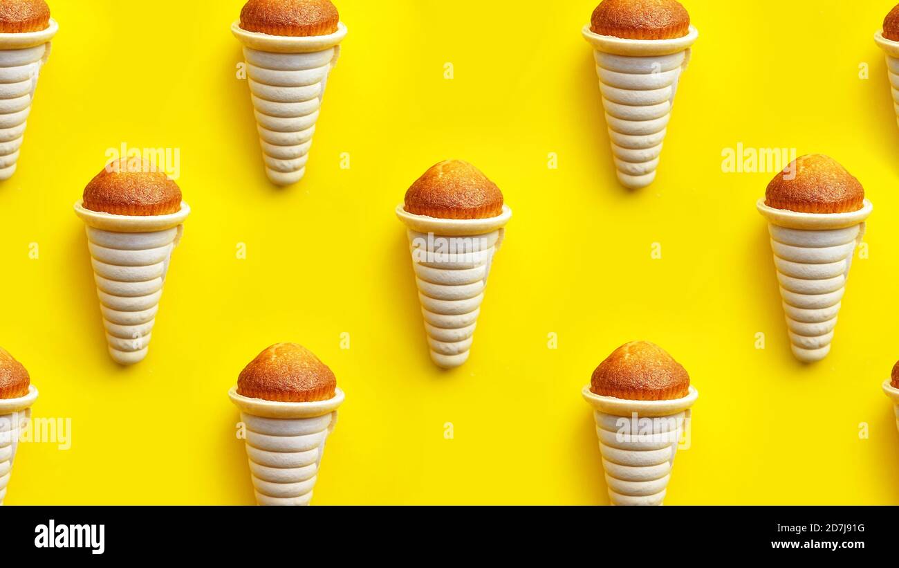 Cono di cialda di icecream e motivo di cupcake isolato su sfondo giallo Foto Stock