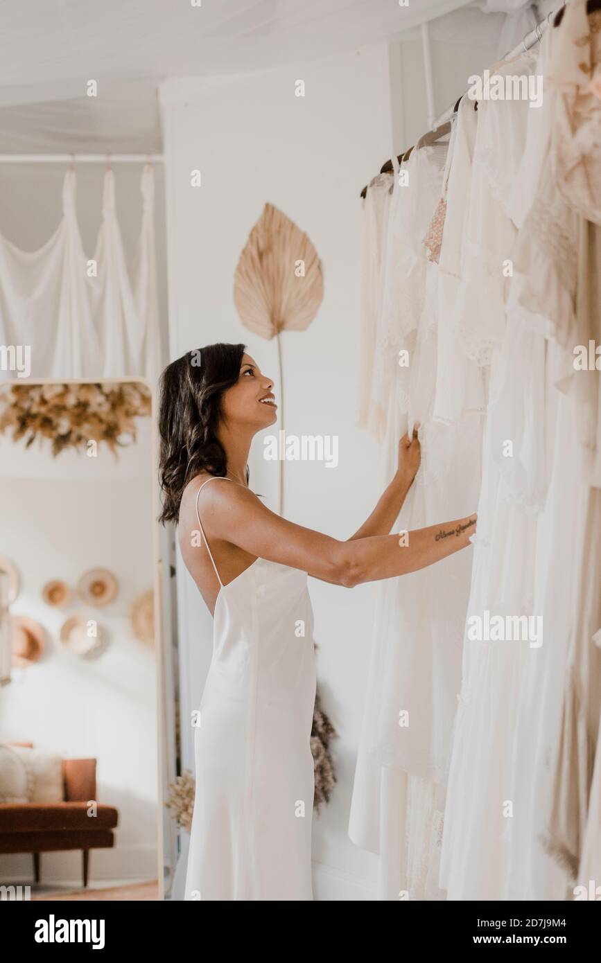 Giovane sposa ammirando l'abito mentre si sta in piedi al negozio di abiti  da sposa Foto stock - Alamy