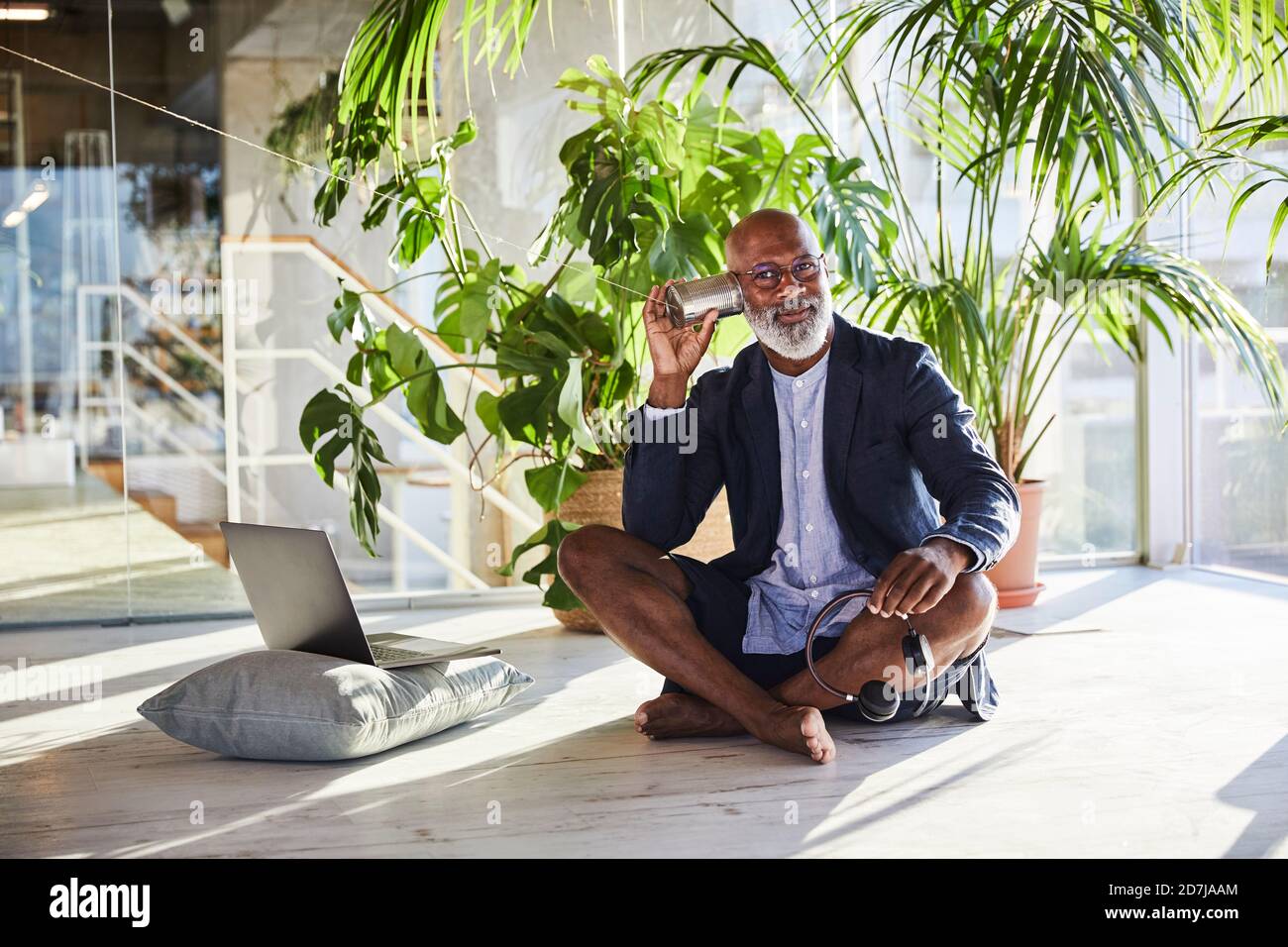 L'uomo maturo che ascolta da Tin può telefonare mentre si siede a. casa Foto Stock