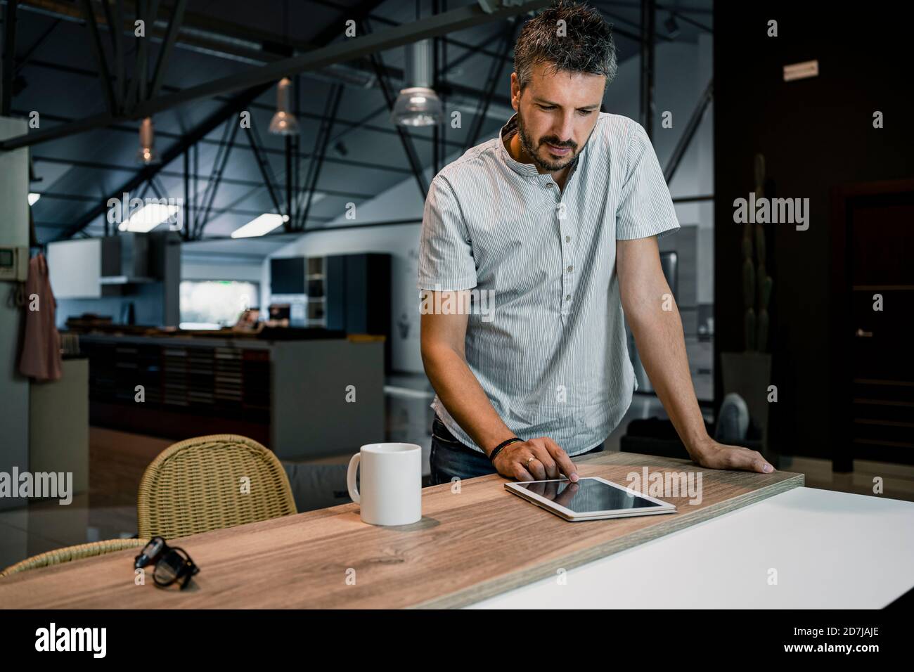 Professionista maschile che utilizza un tablet digitale mentre lavora in freelance scrivania in ufficio Foto Stock