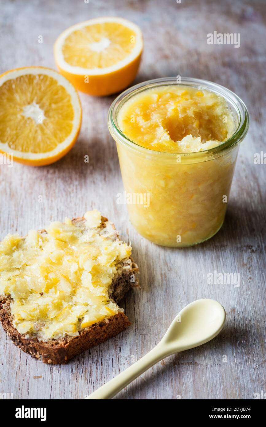 Marmellata d'arancia tenuta da pane e fette d'arancia sul tavolo Foto Stock