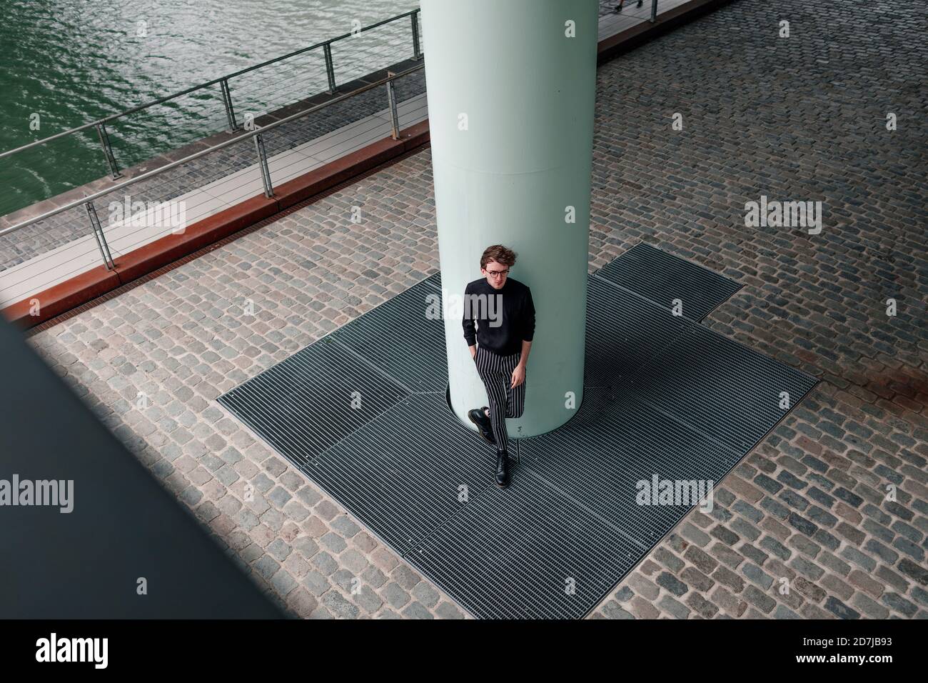 Giovane pensieroso in piedi per colonna in città Foto Stock