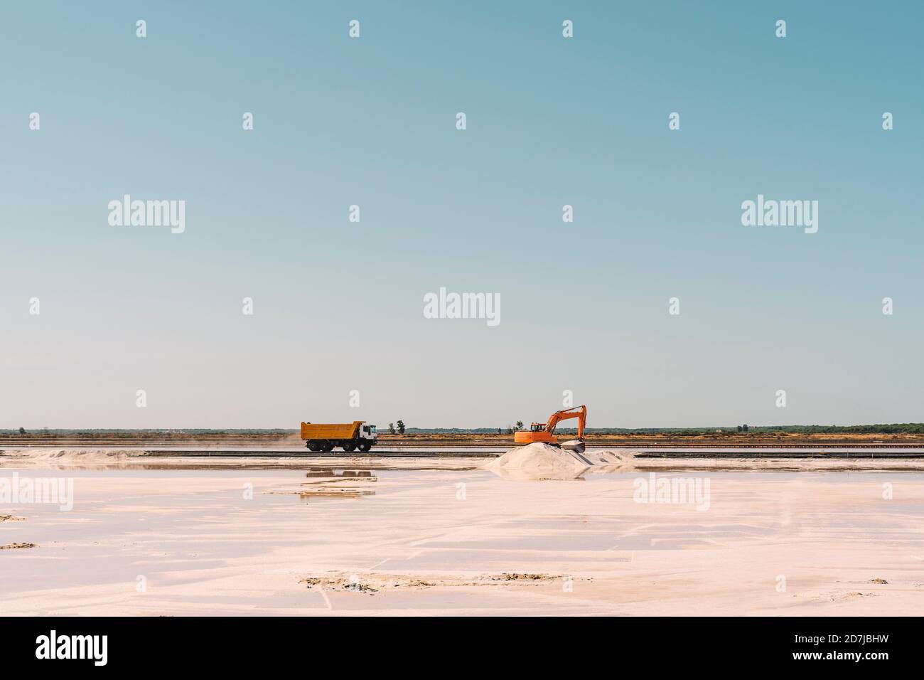 Spagna, Provincia di Huelva, Huelva, cielo chiaro sopra camion e moto di terra che lavorano in piano di sale Foto Stock