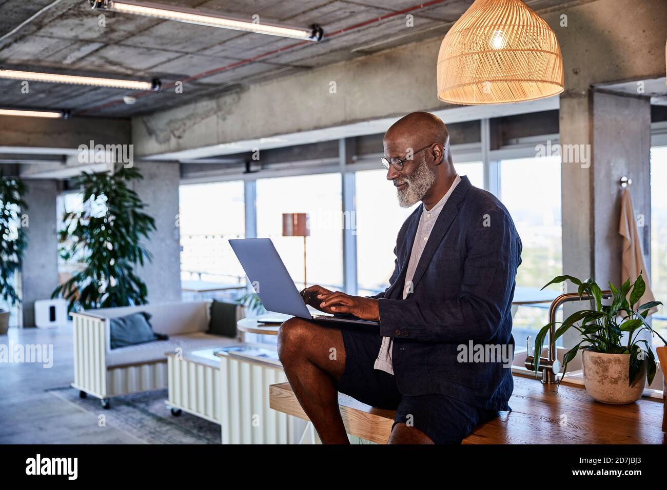 Uomo che lavora su un computer portatile mentre è seduto a casa Foto Stock